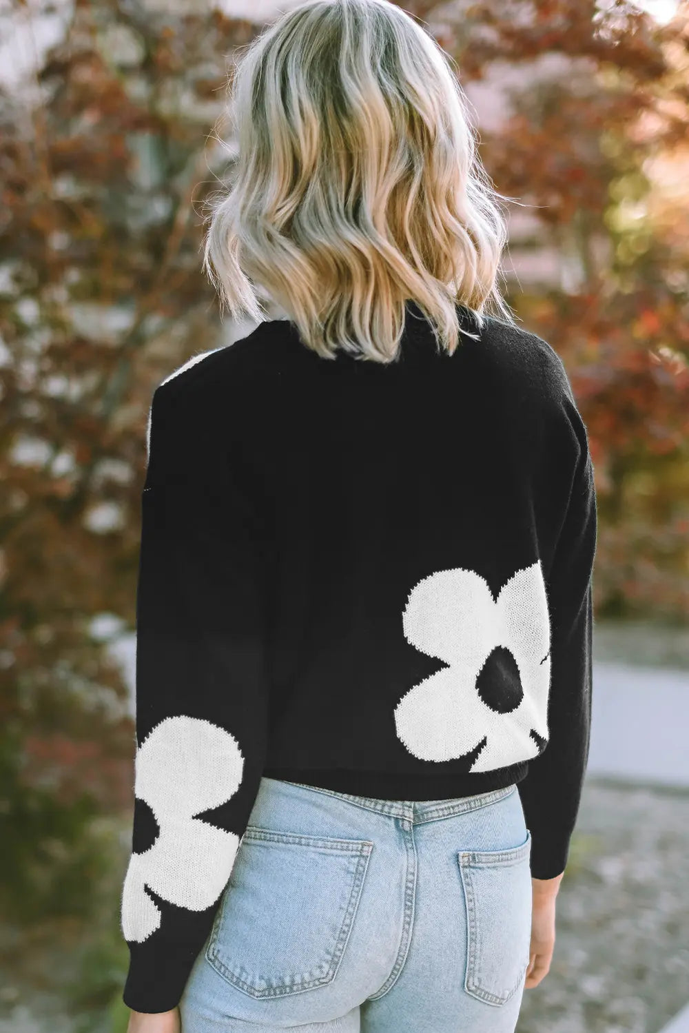 Black long-sleeve sweater with white floral pattern, viewed from the back