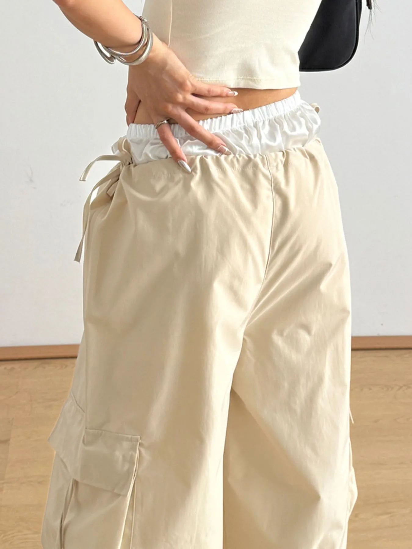 Tan cargo pants featuring elastic waist, front flap pockets, and side drawcord ties