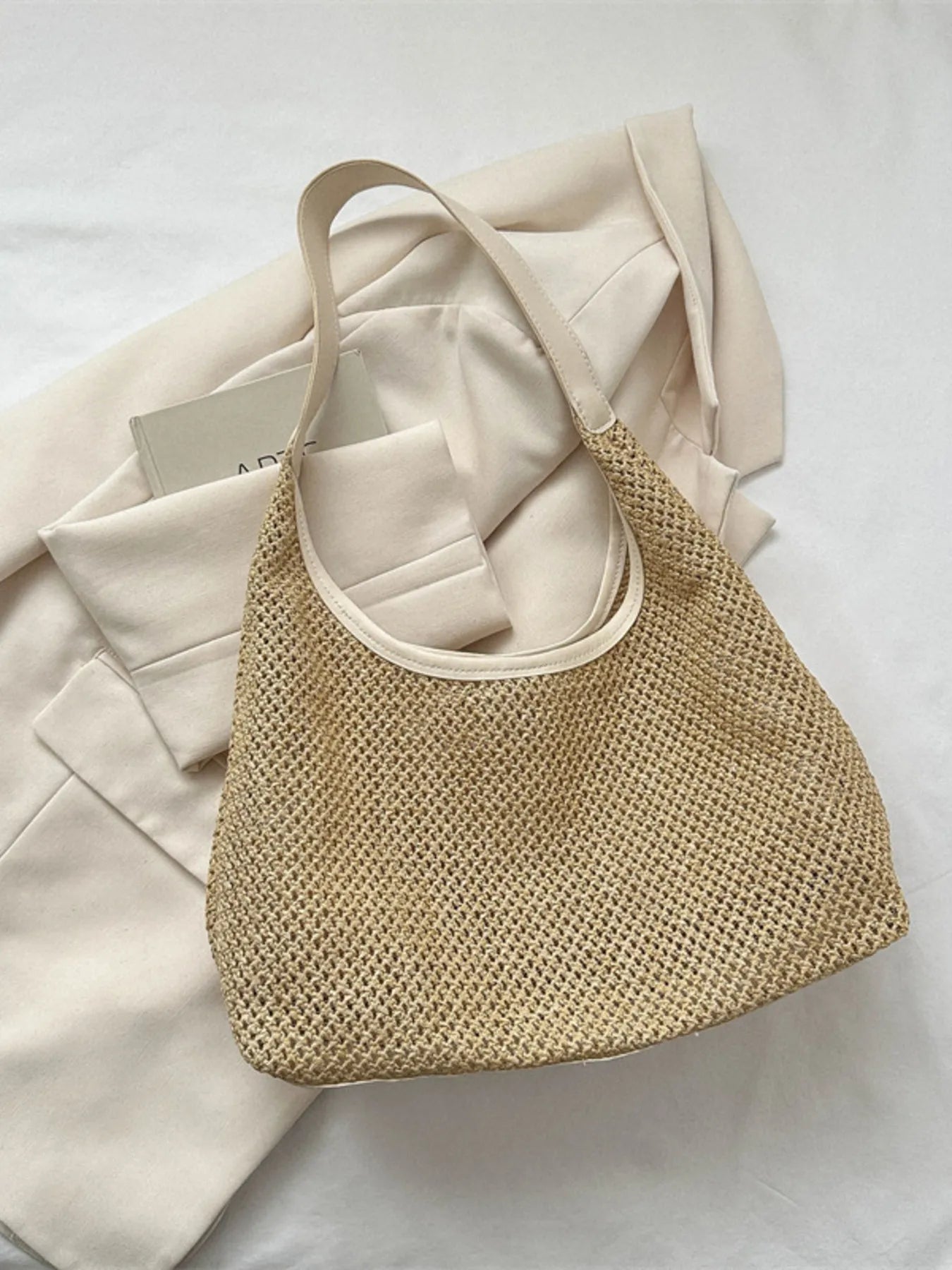 Woven straw shoulder bag in tan with light beige handles, hobo style