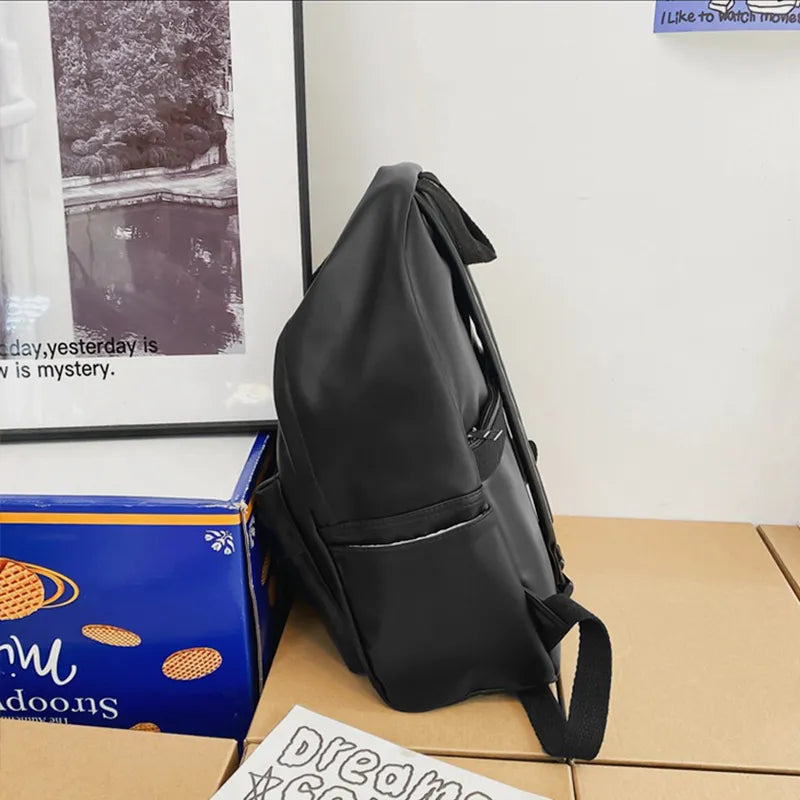 Black vegan leather zip backpack with curved top flap and front pocket