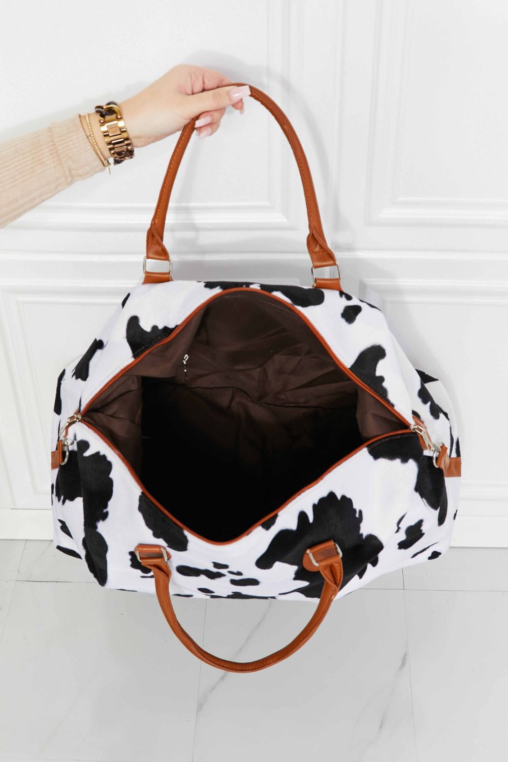 Open cow print plush weekender bag with brown interior and tan leather-look handles