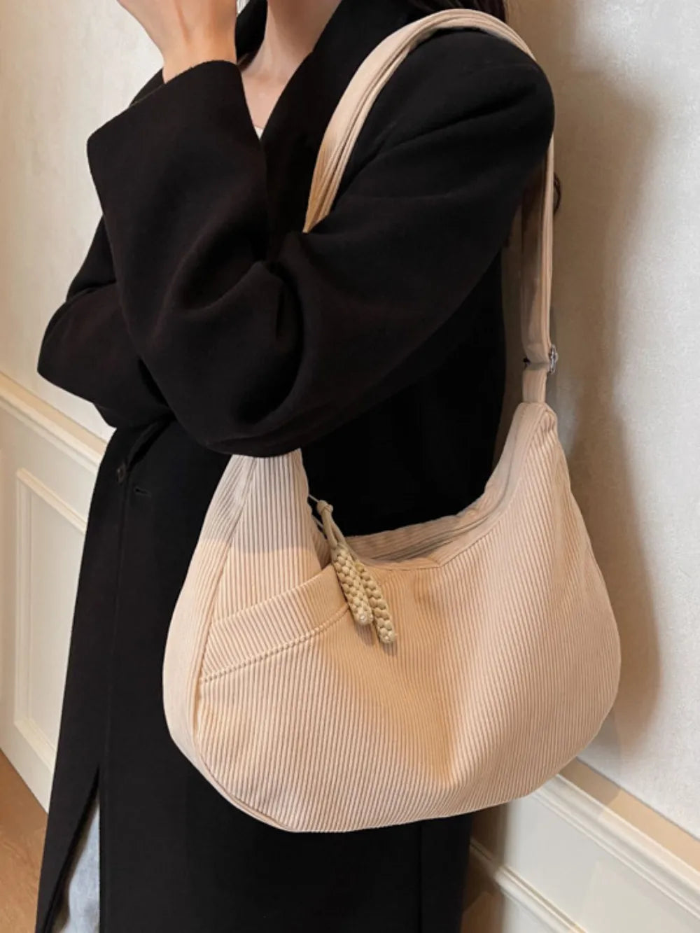 Beige ribbed hobo shoulder bag worn crossbody style with adjustable strap