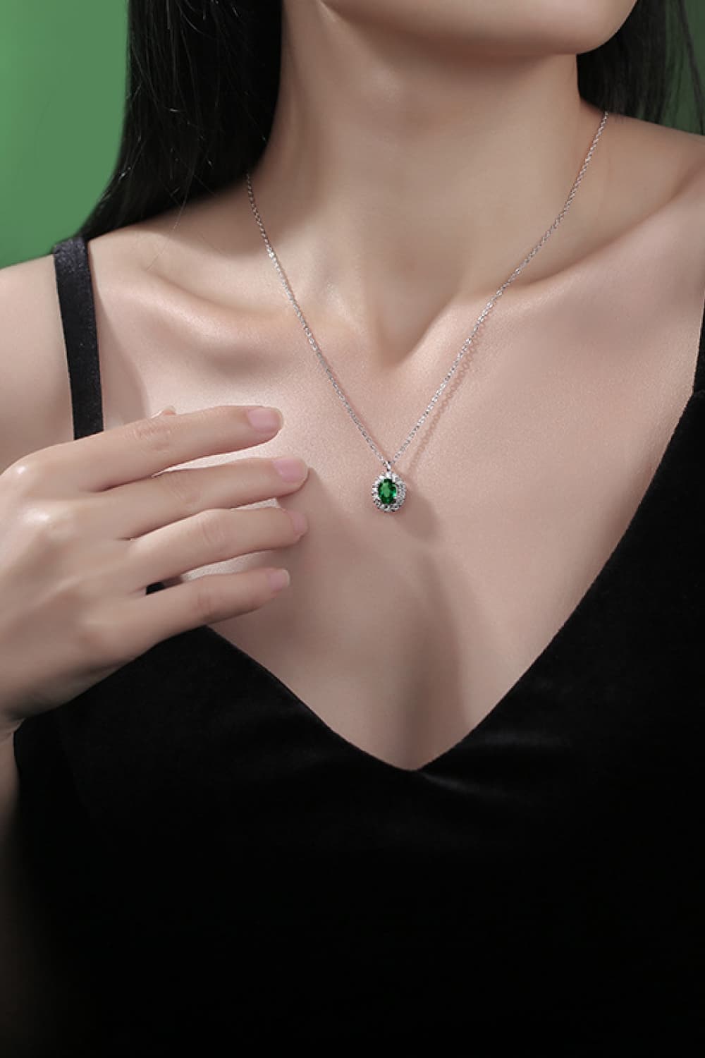 Sterling silver necklace with green emerald pendant worn on neckline
