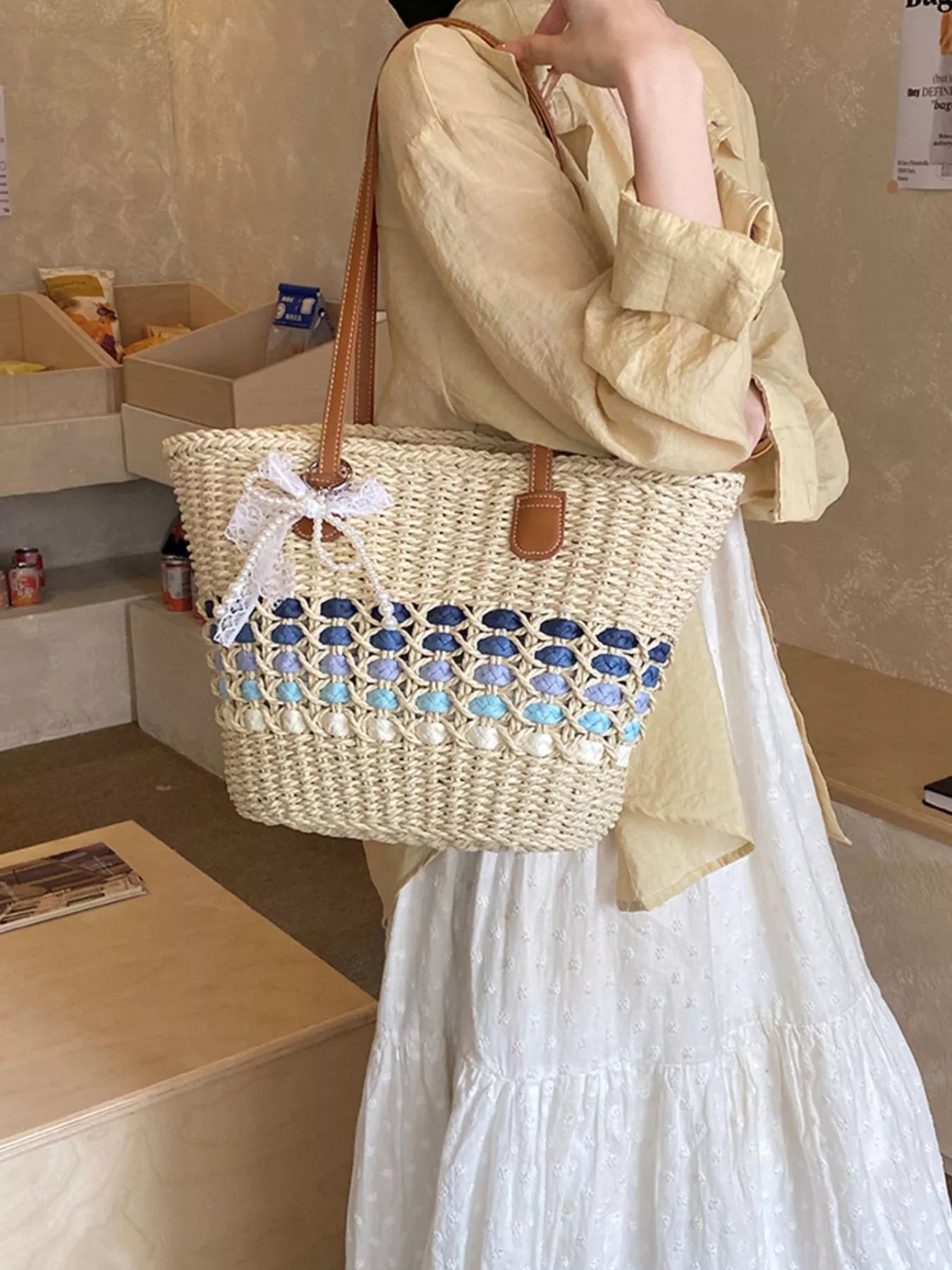 Woven straw shoulder bag with blue-and-aqua crochet lattice band, brown leather straps