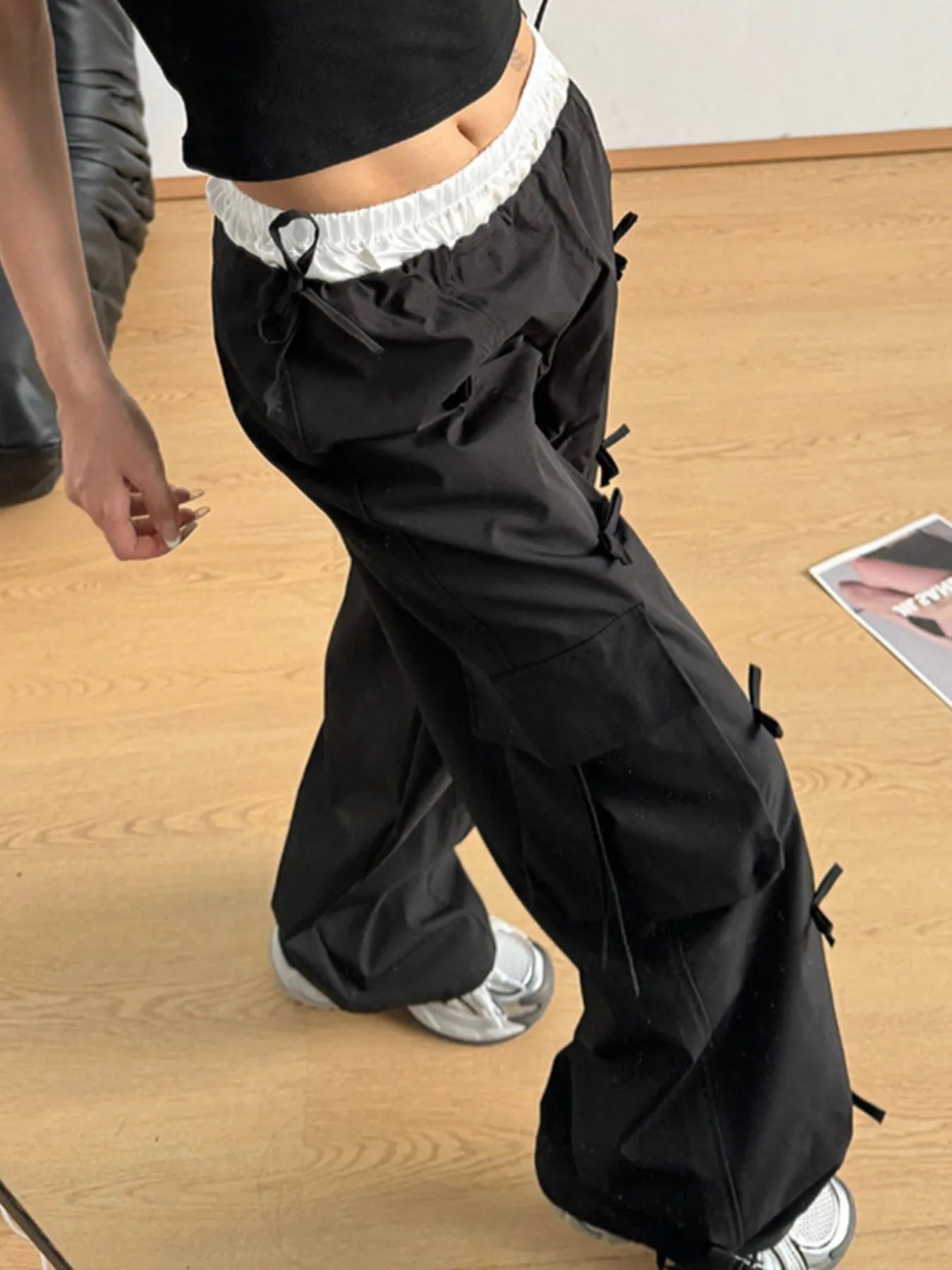 Black cargo pants with elastic waistband, flap cargo pockets, and dangling tie cords