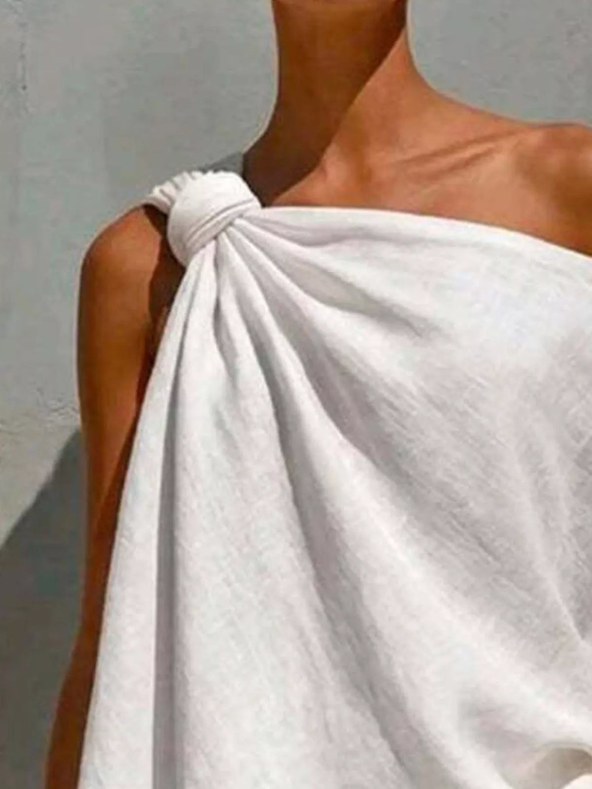 White one-shoulder blouse close-up showing knotted neckline and soft drape