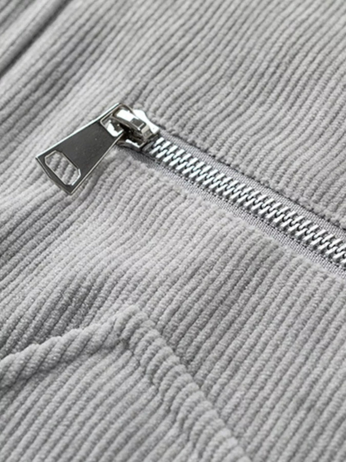Close-up of gray corduroy zipper with metal pull and stitched placket