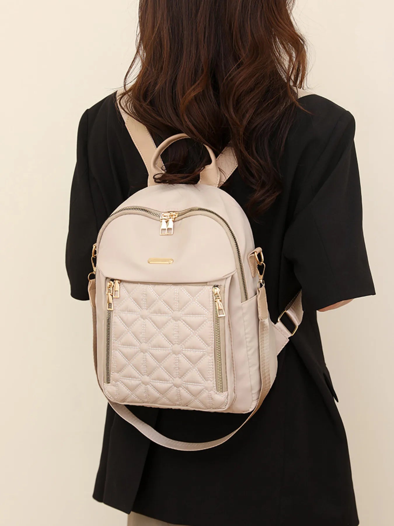 Eggshell quilted oxford backpack worn with adjustable shoulder straps, front zip pocket