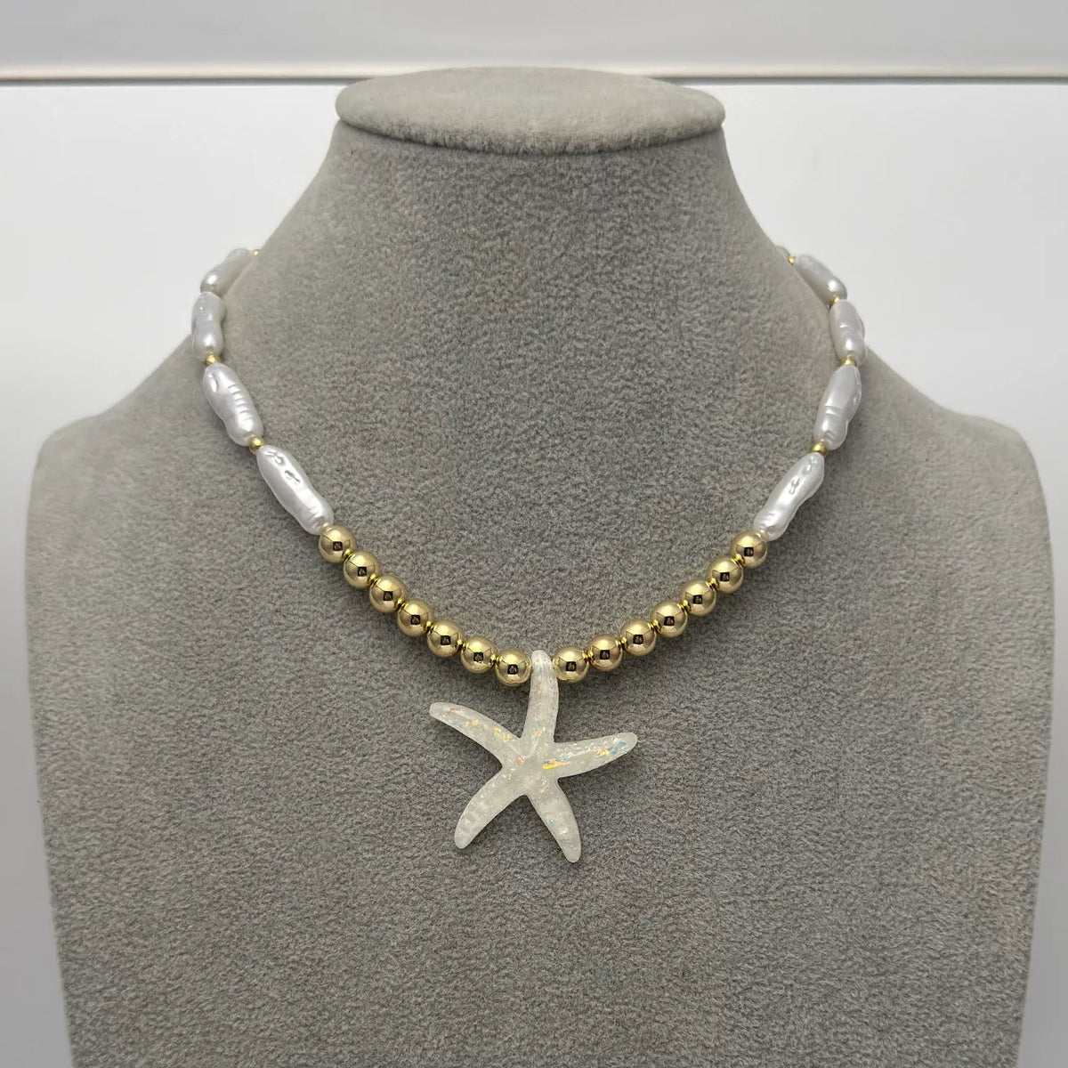 Starfish pendant necklace on bust: white starfish with pearl-look and gold beads