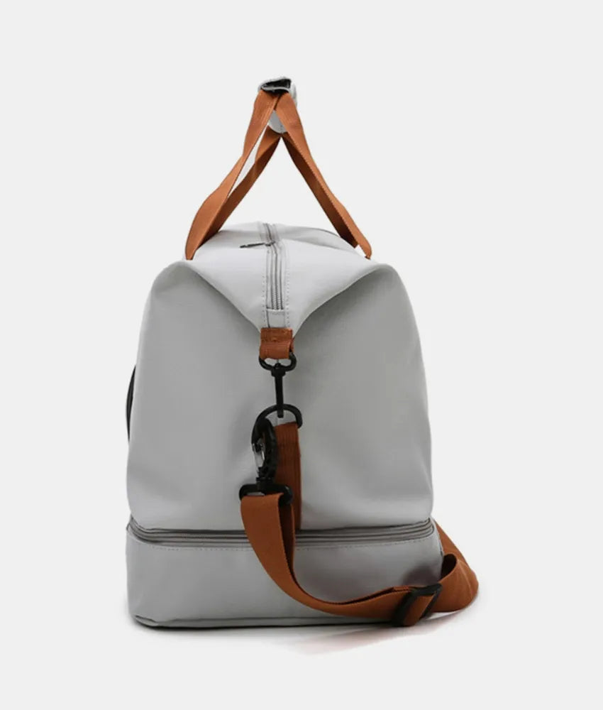 Oversize travel duffle bag in light gray with brown strap handles and front zipper