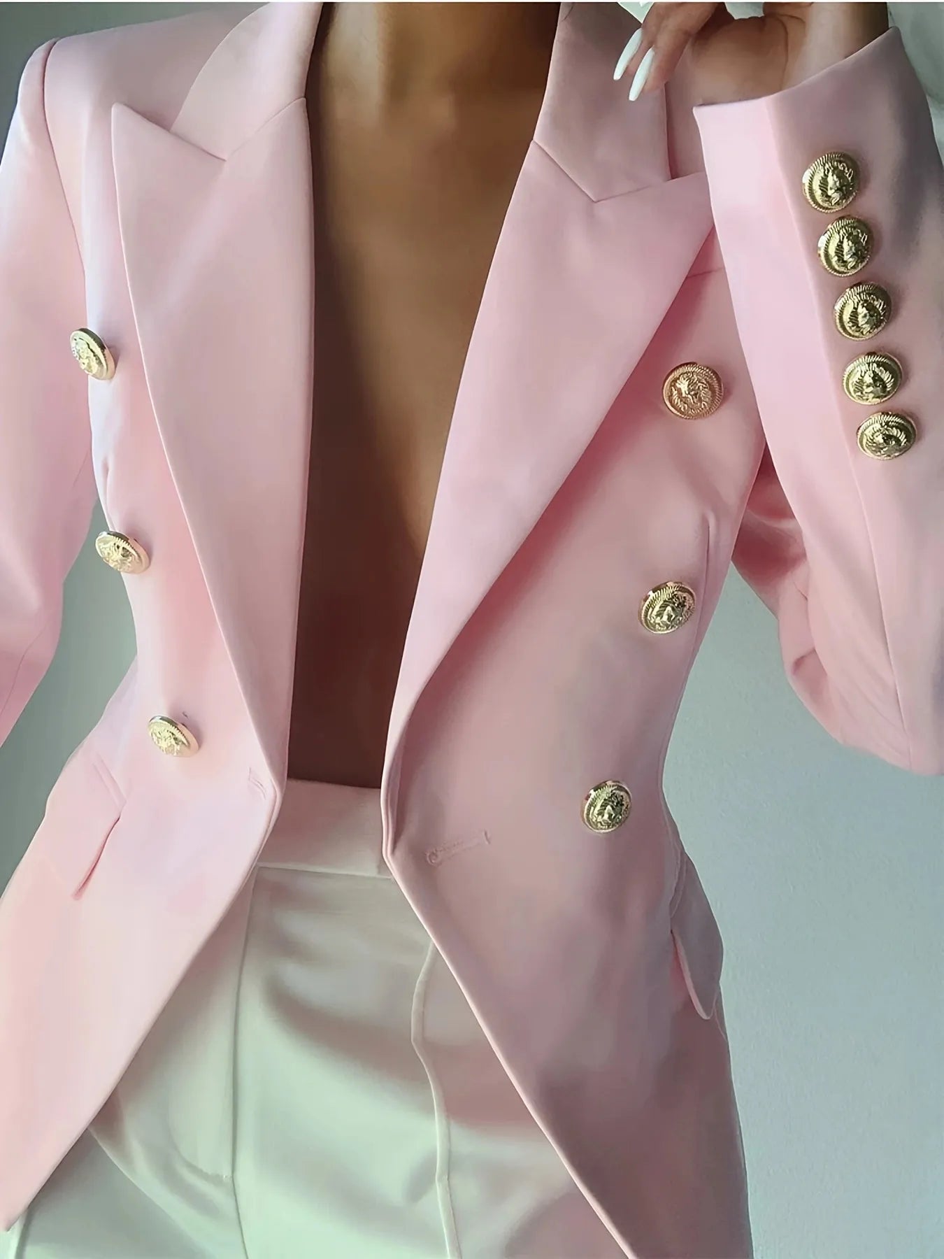 Light pink blazer with gold button accents, V-neck lapels, and front pockets