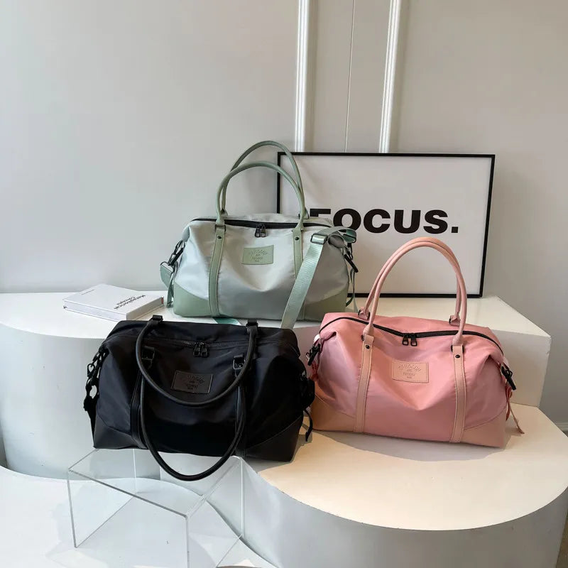 Set of polyester travel duffel bags in sage, black, and blush pink with handles and straps