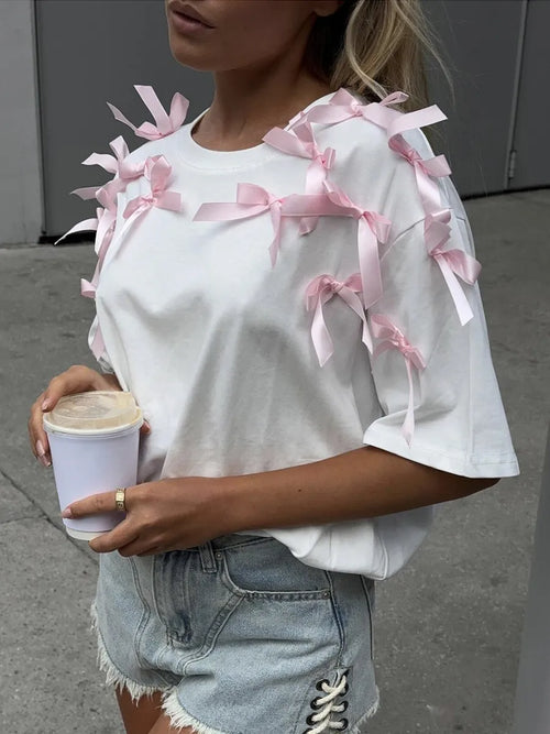 White short sleeve T-shirt with pink bow ribbon details across the shoulders