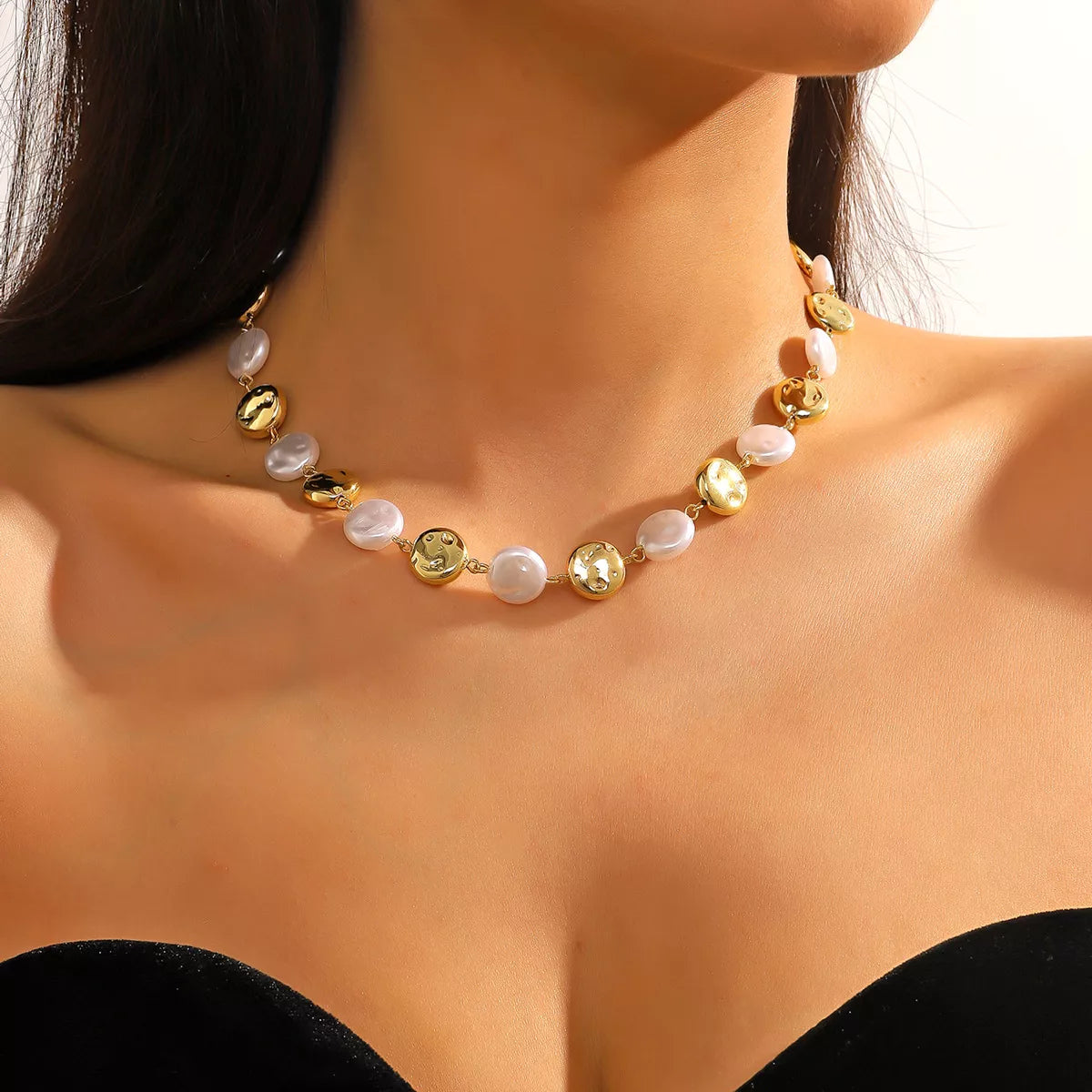 Pearl chain necklace with gold-tone coin beads and white pearl beads, worn on the neck