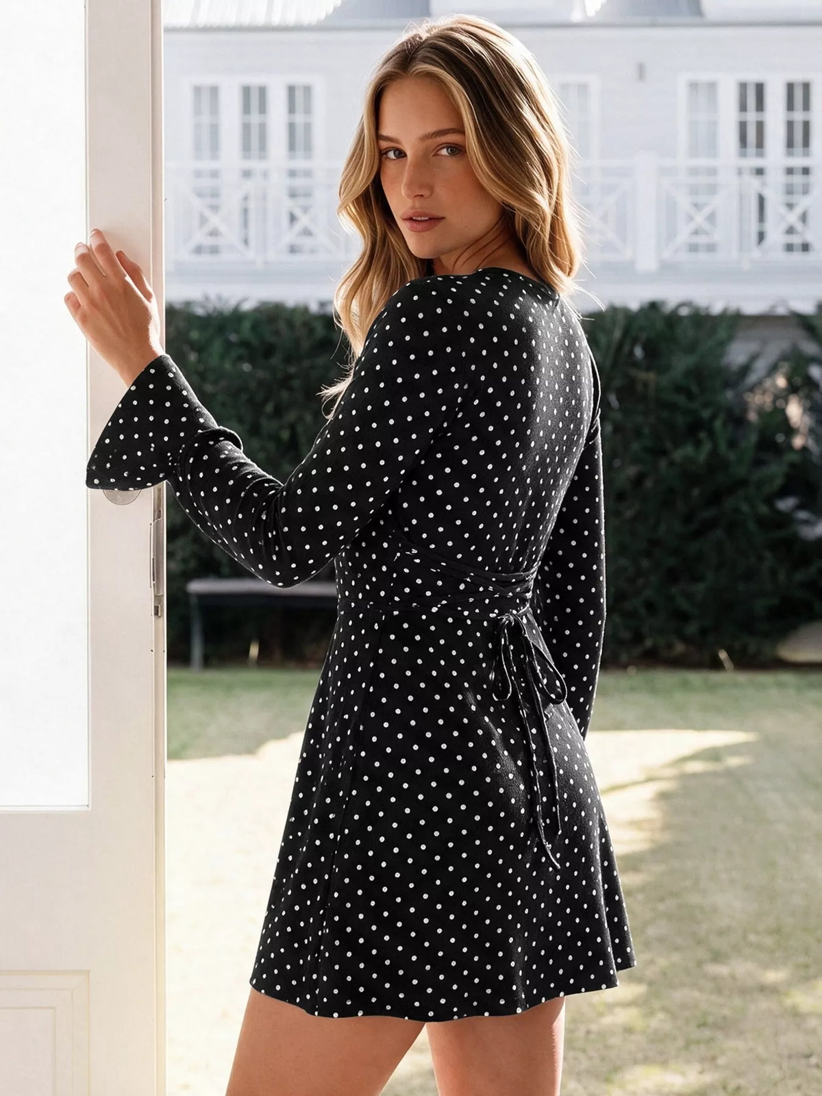 Black polka dot long-sleeve mini dress with V-neck, side tie, and flared skirt