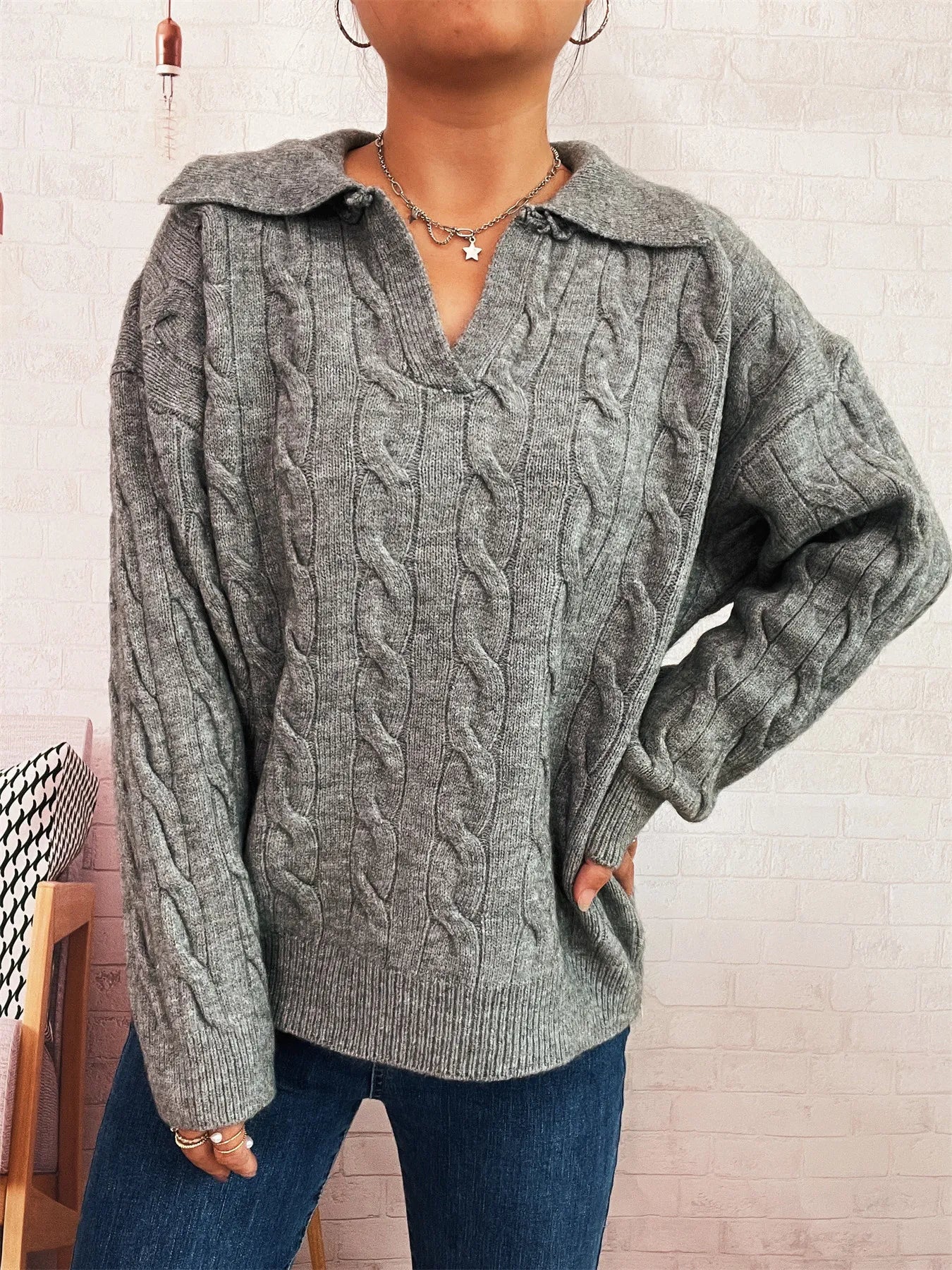 Gray cable-knit johnny-collar sweater with long sleeves, chunky cable pattern and V neckline.