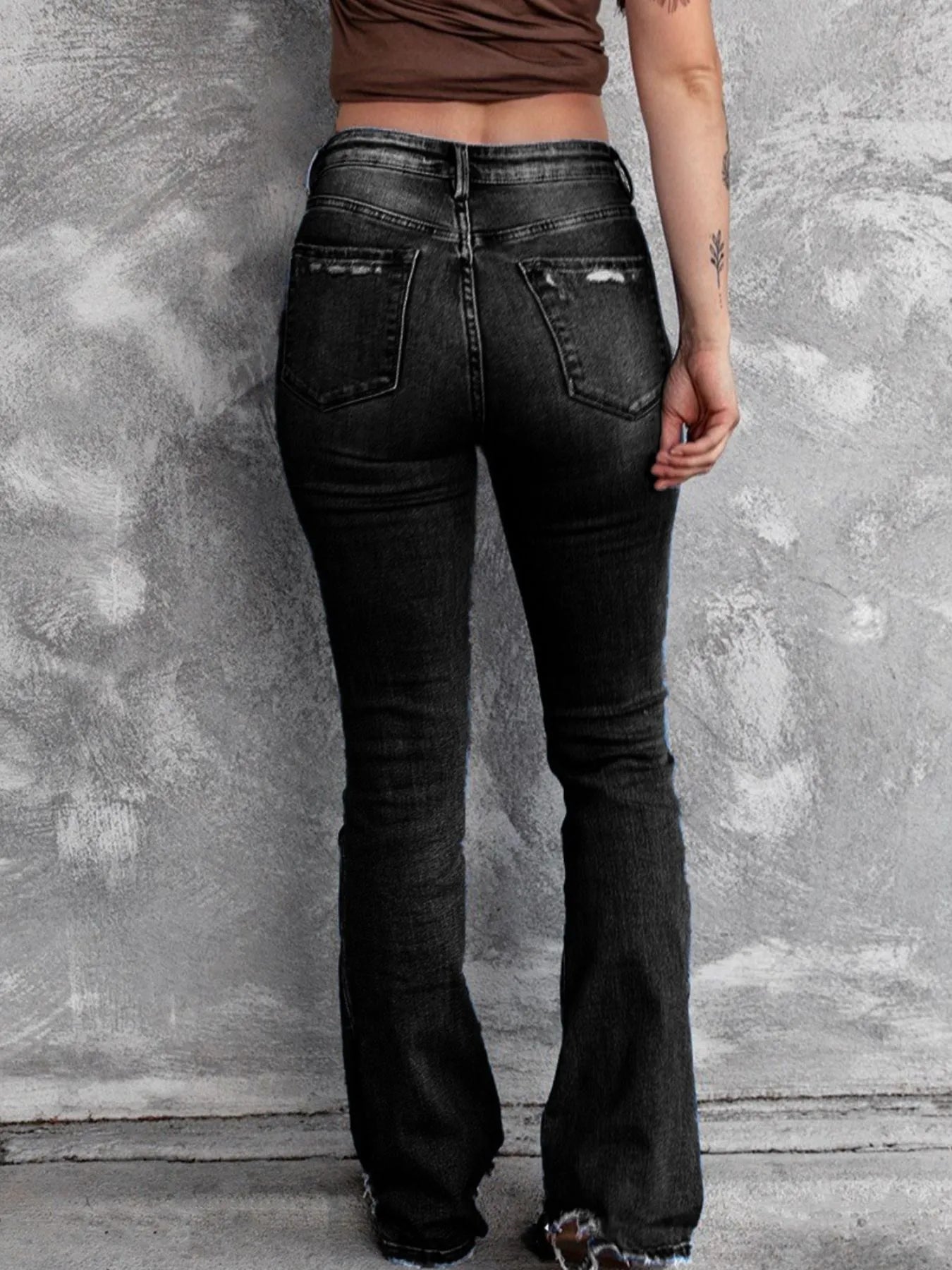 Black distressed flare jeans with worn patches and wide leg opening, front pockets.