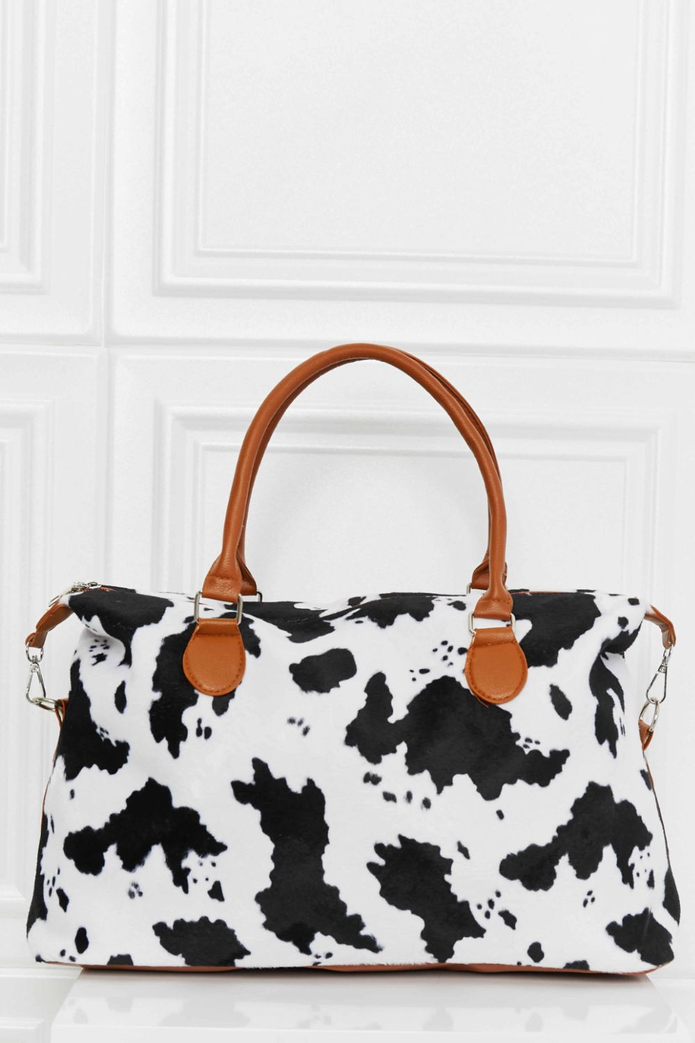 Cow print brushed weekender bag with brown handles and zip-top closure