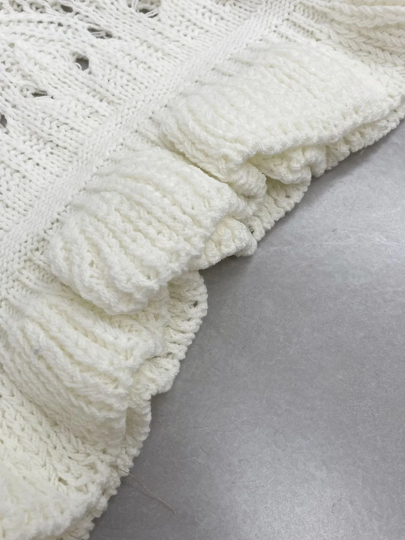 Close-up of white crocheted sleeve cuff with ribbed ruffle trim edge
