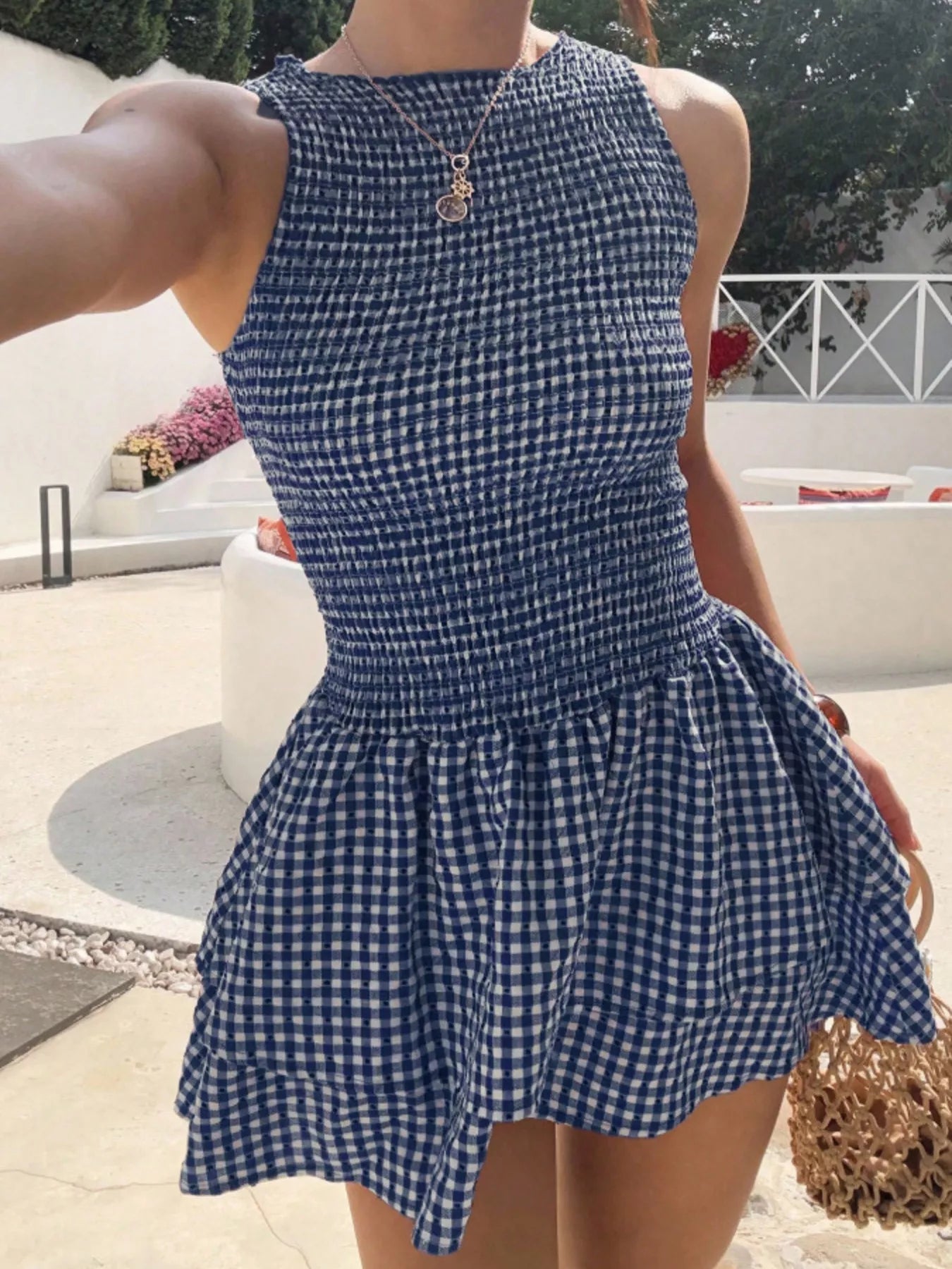 Gingham smocked mini dress, blue and white, sleeveless with a ruffled bodice and flowy skirt.