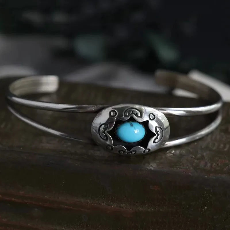 Silver open cuff bracelet with oval blue cabochon center and decorative metalwork