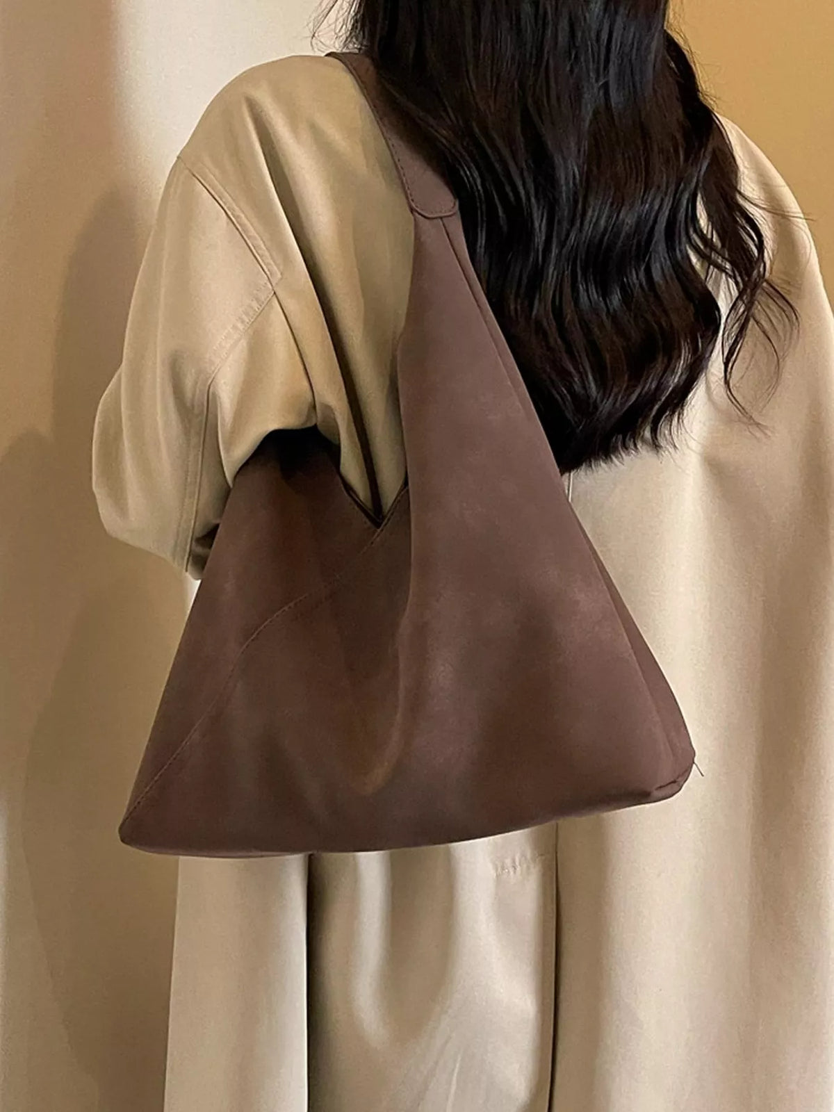 Brown slouchy suede shoulder bag worn on the shoulder, angled view
