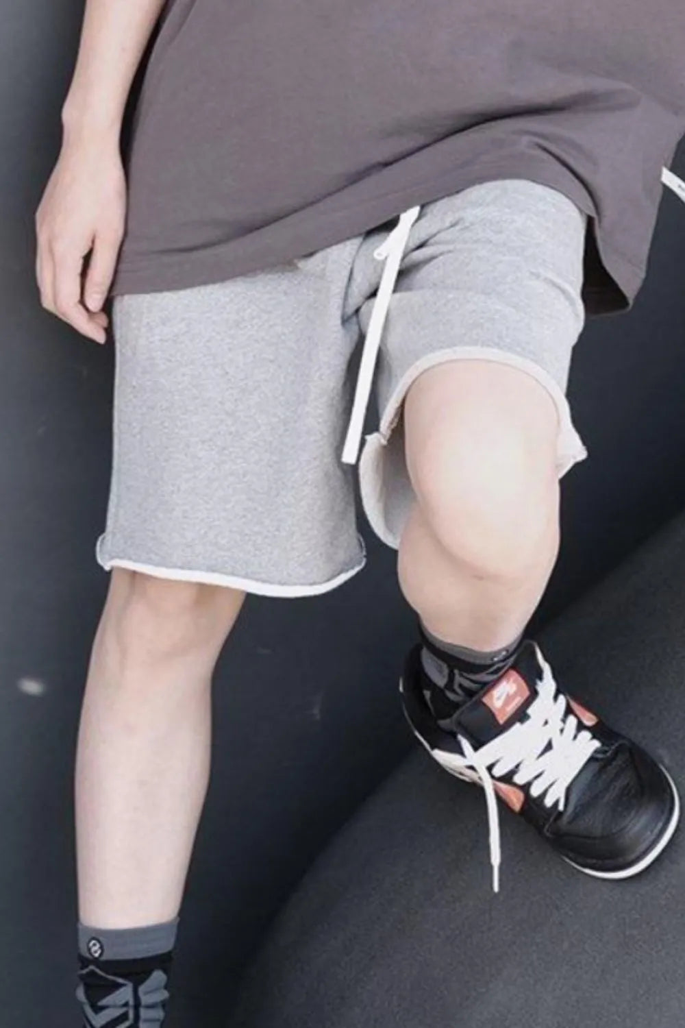 Gray drawstring shorts with elastic waistband and white drawcord, above-knee cut.