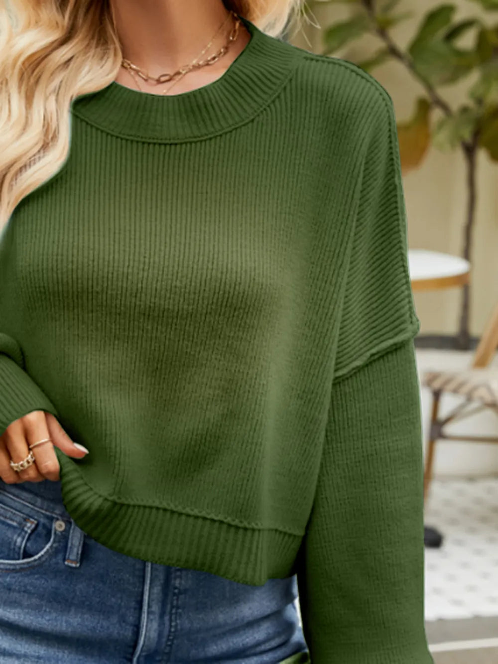 Green knit sweater with round crew neck and lantern sleeves, close-up