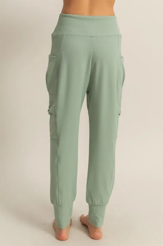 Sage green high-waist sweatpants with cargo-style side pockets and tapered legs