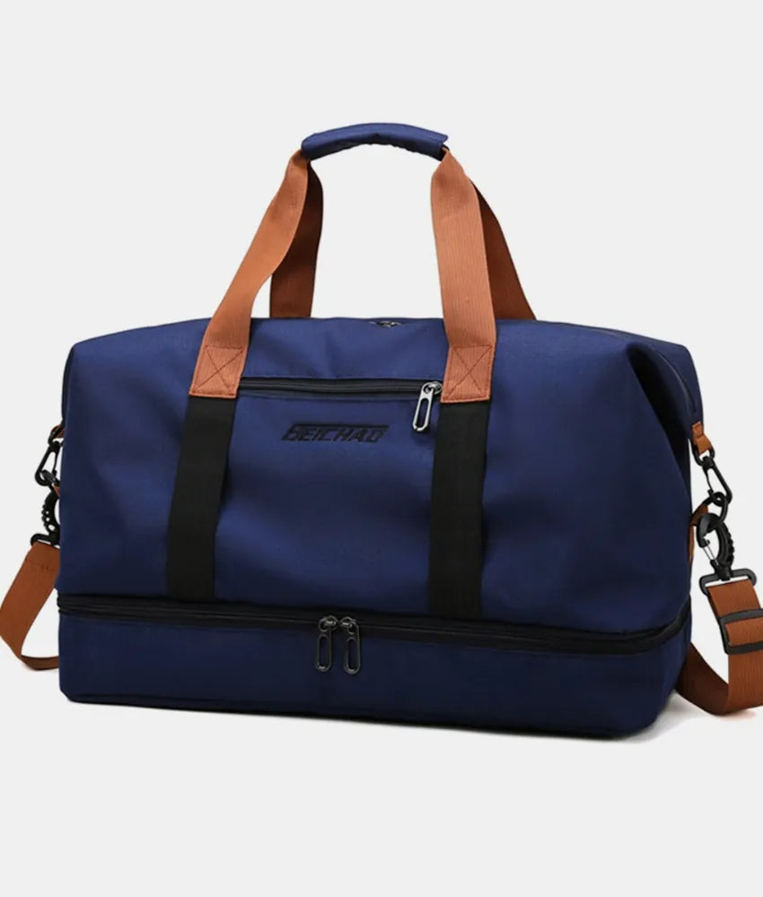 Dark navy oversize travel duffle bag with tan handles, crossbody strap, and zipper
