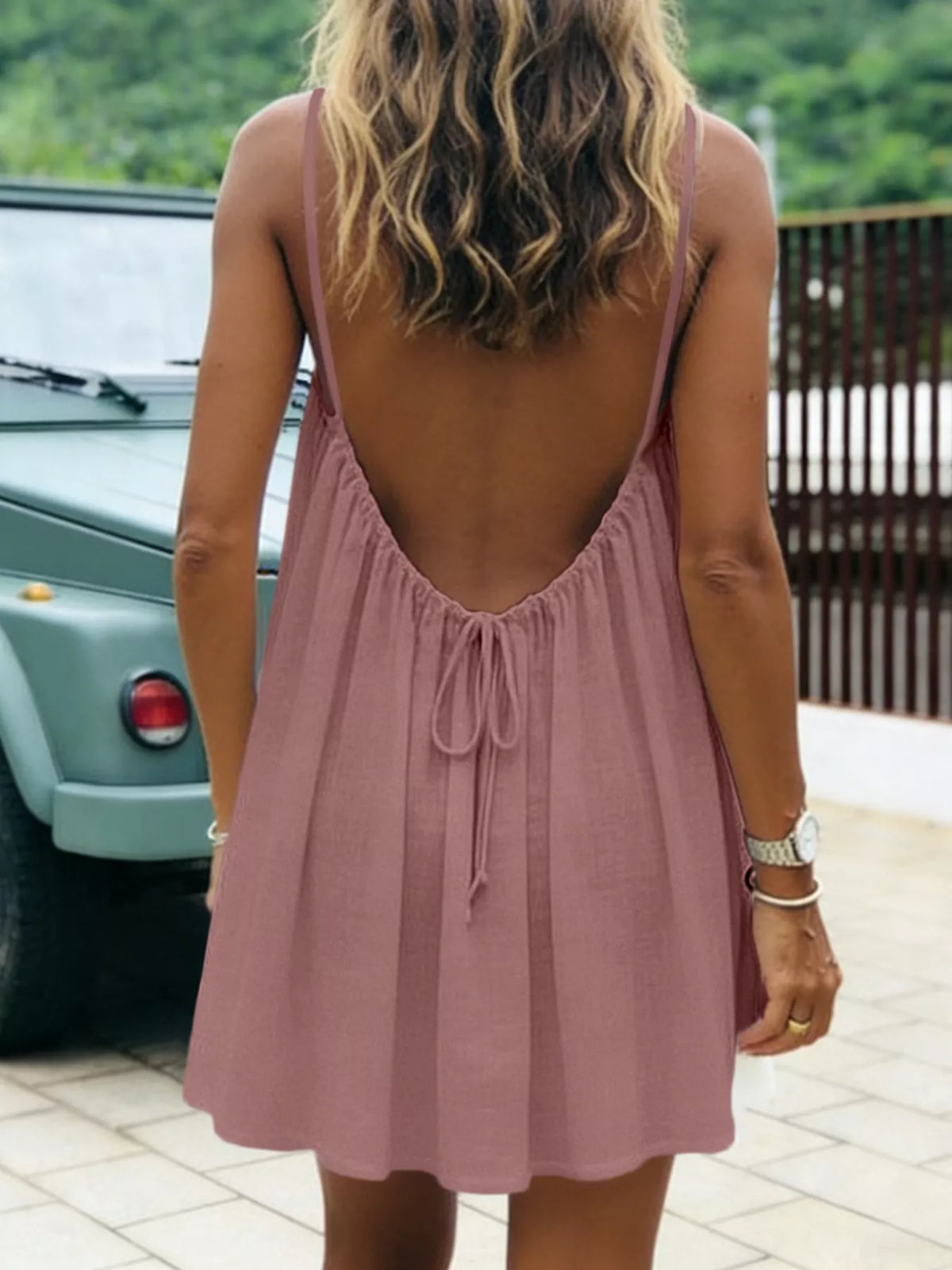 Backless spaghetti-strap ruched mini dress in dusty mauve, open back with drawstring tie.