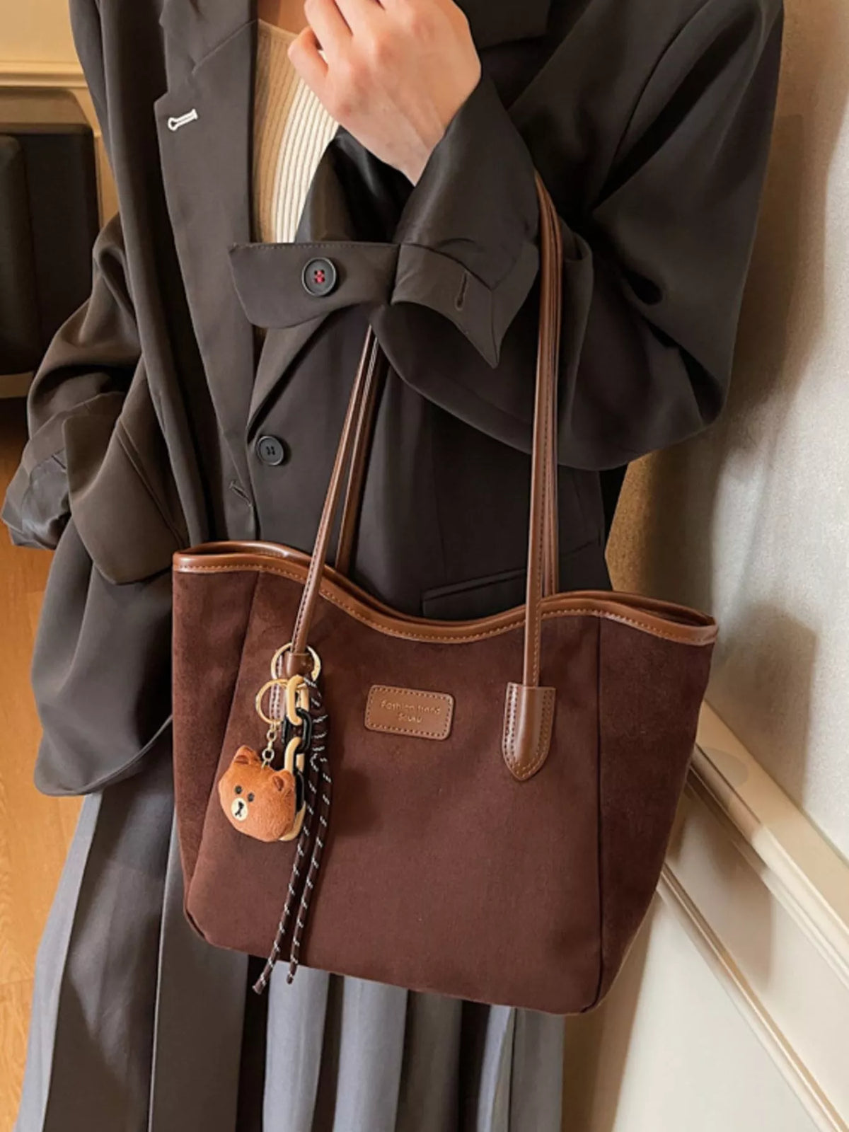 Brown suede tote bag with wide straps, front tab pocket, hanging bear keychain