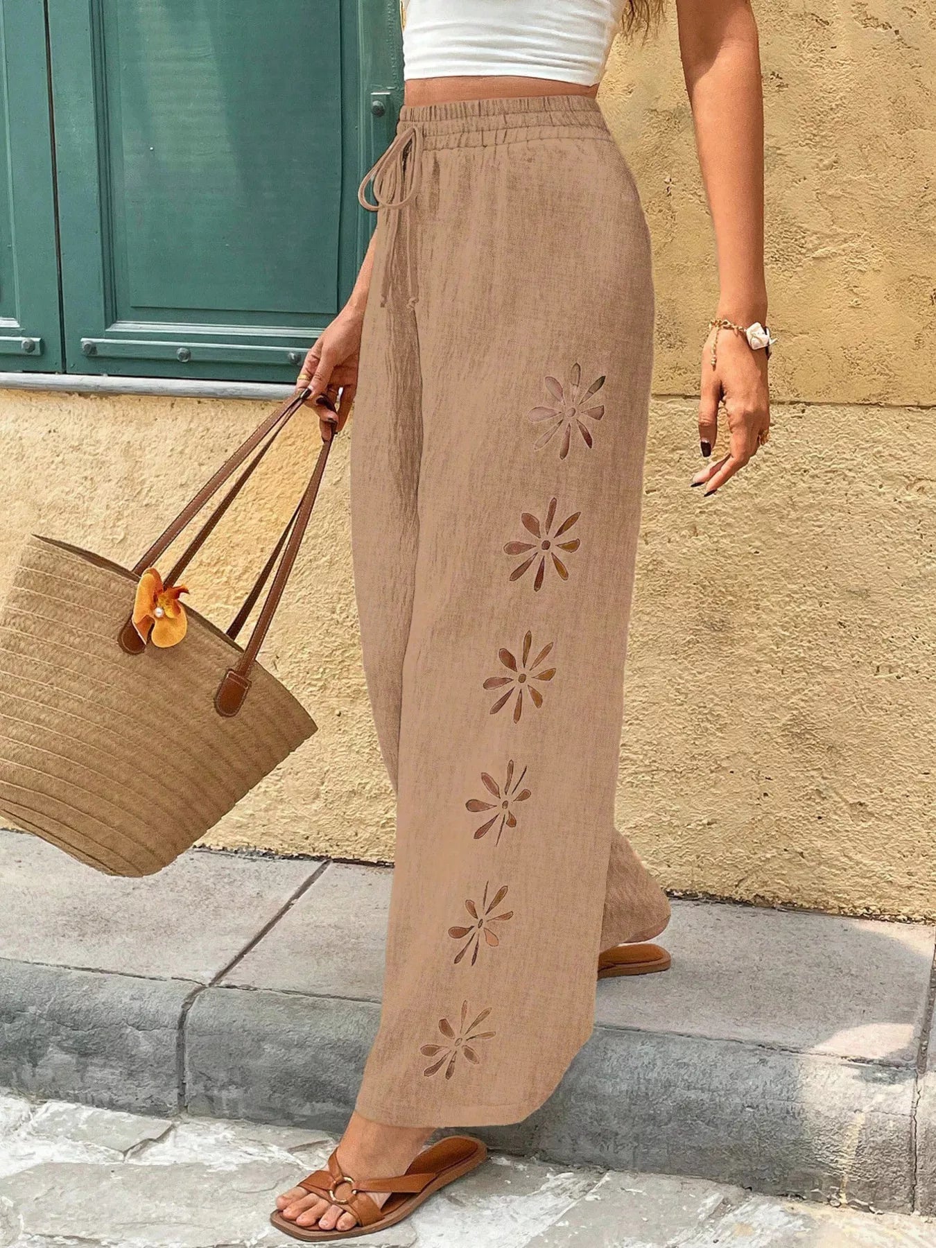 Light brown wide-leg pants with drawstring waist and floral cutout detail on legs
