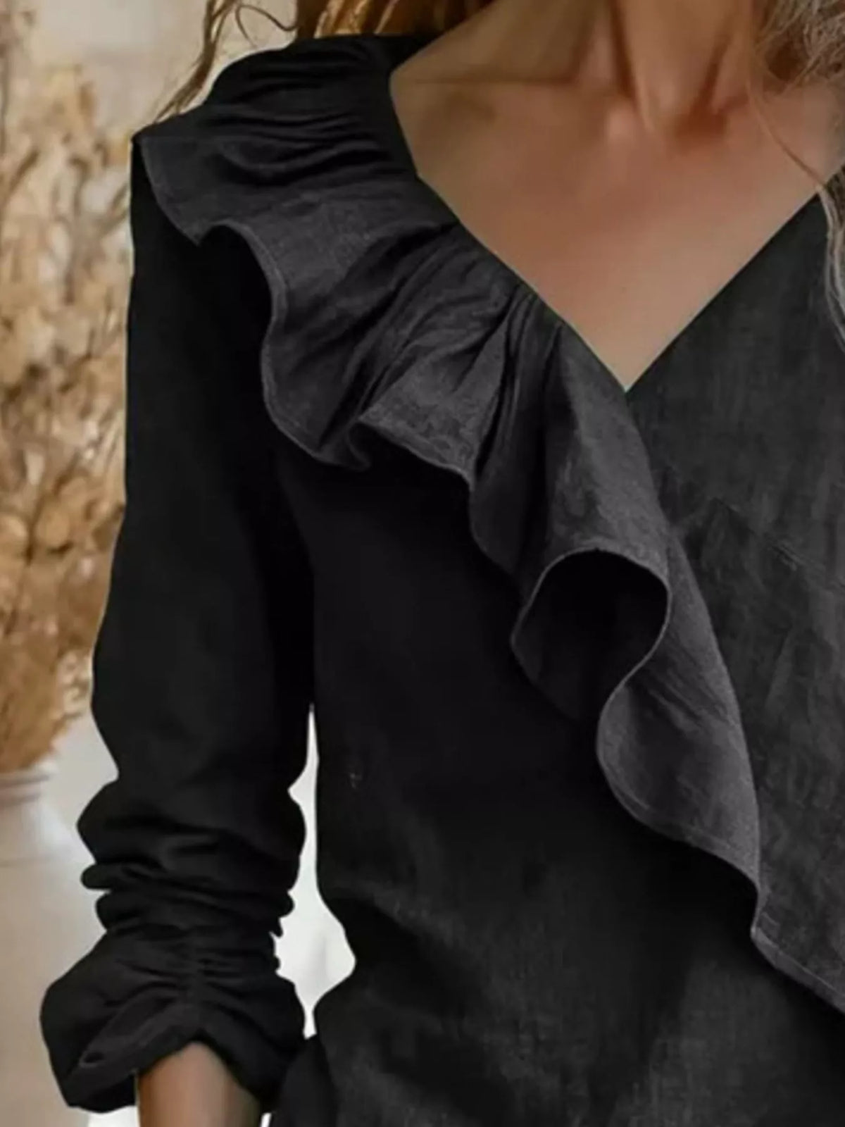 Black ruffled V-neck long-sleeve blouse, close-up of layered ruffle detail