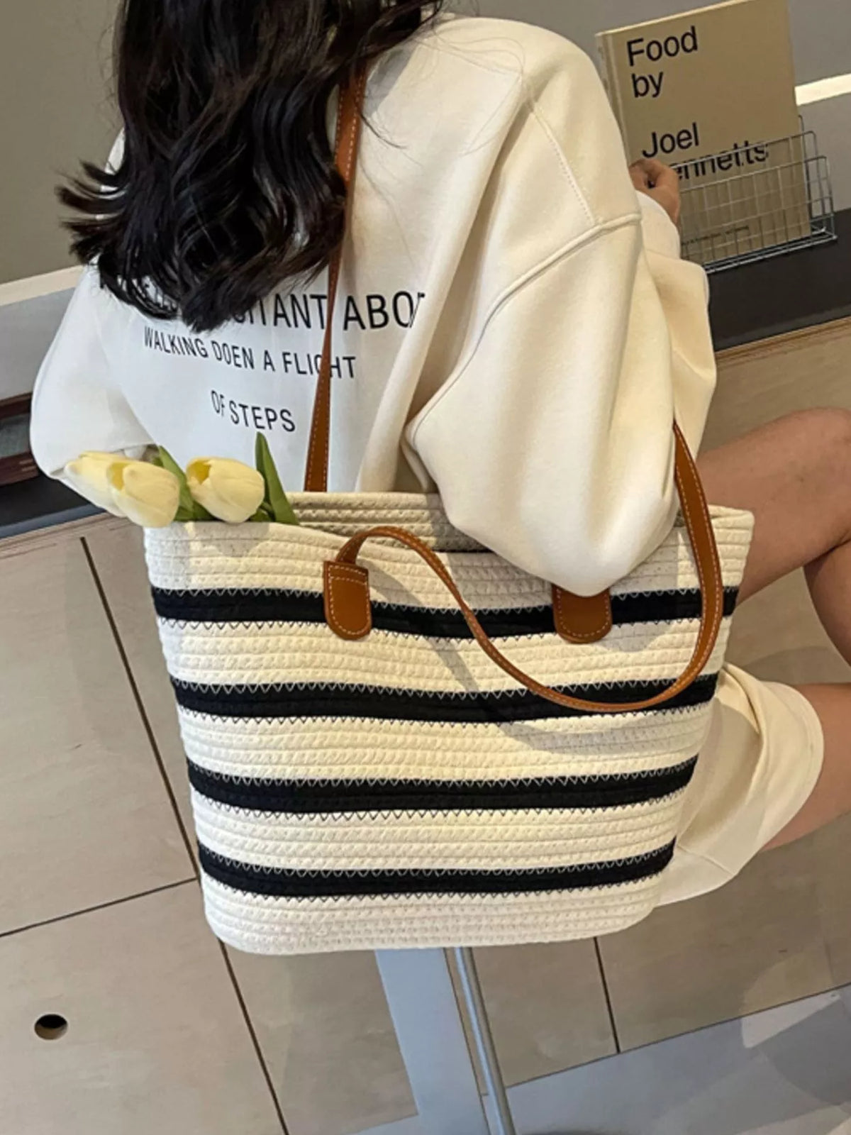 Striped straw tote bag with brown leather strap and top handles, navy and white stripes