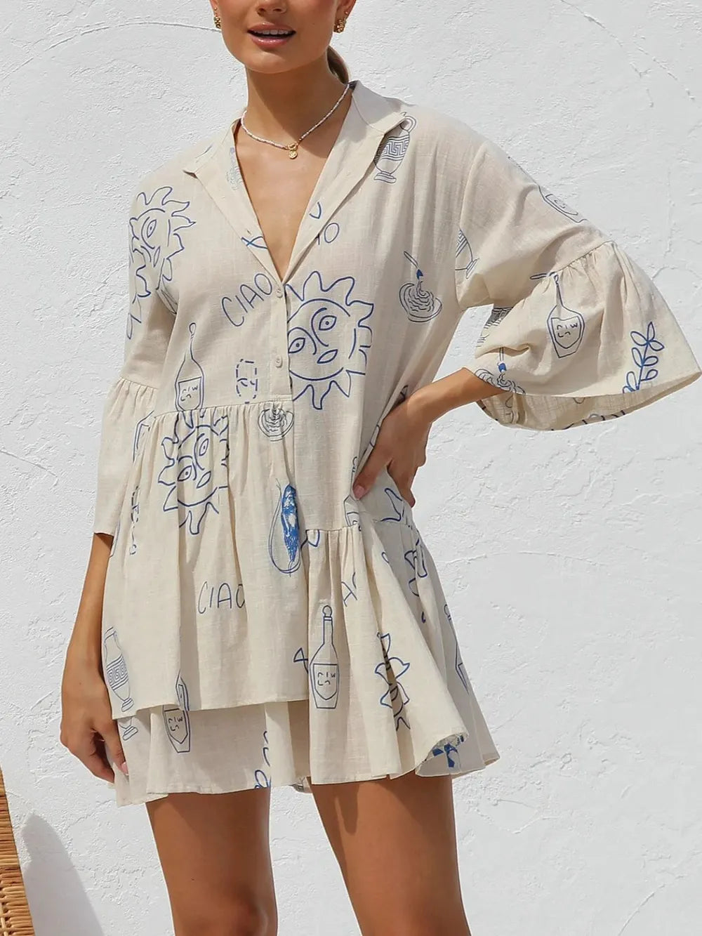 Cream printed mini dress with blue doodles, button-front V-neck, and flared skirt