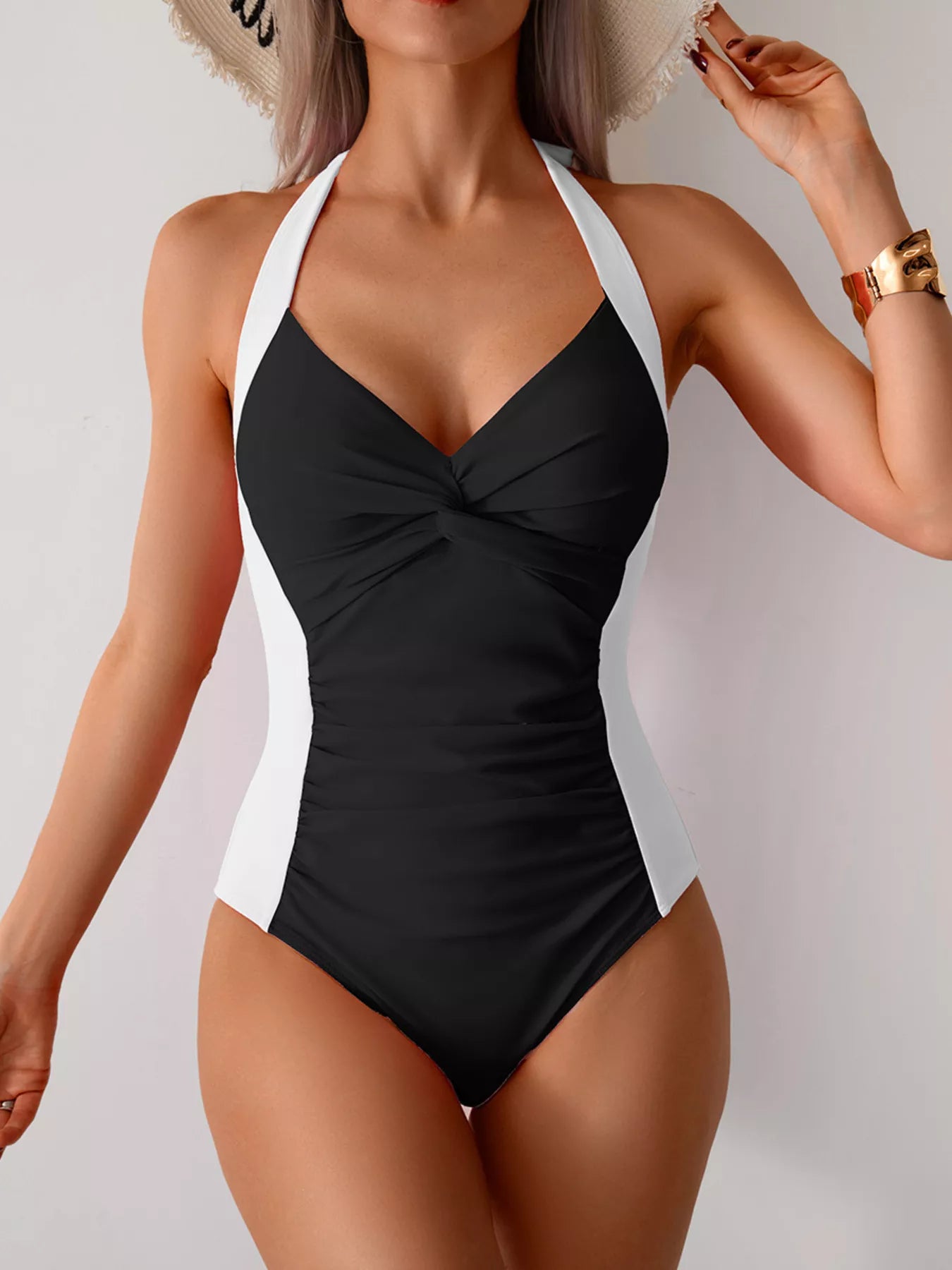Black halter one-piece swimsuit with twisted front and white side panels
