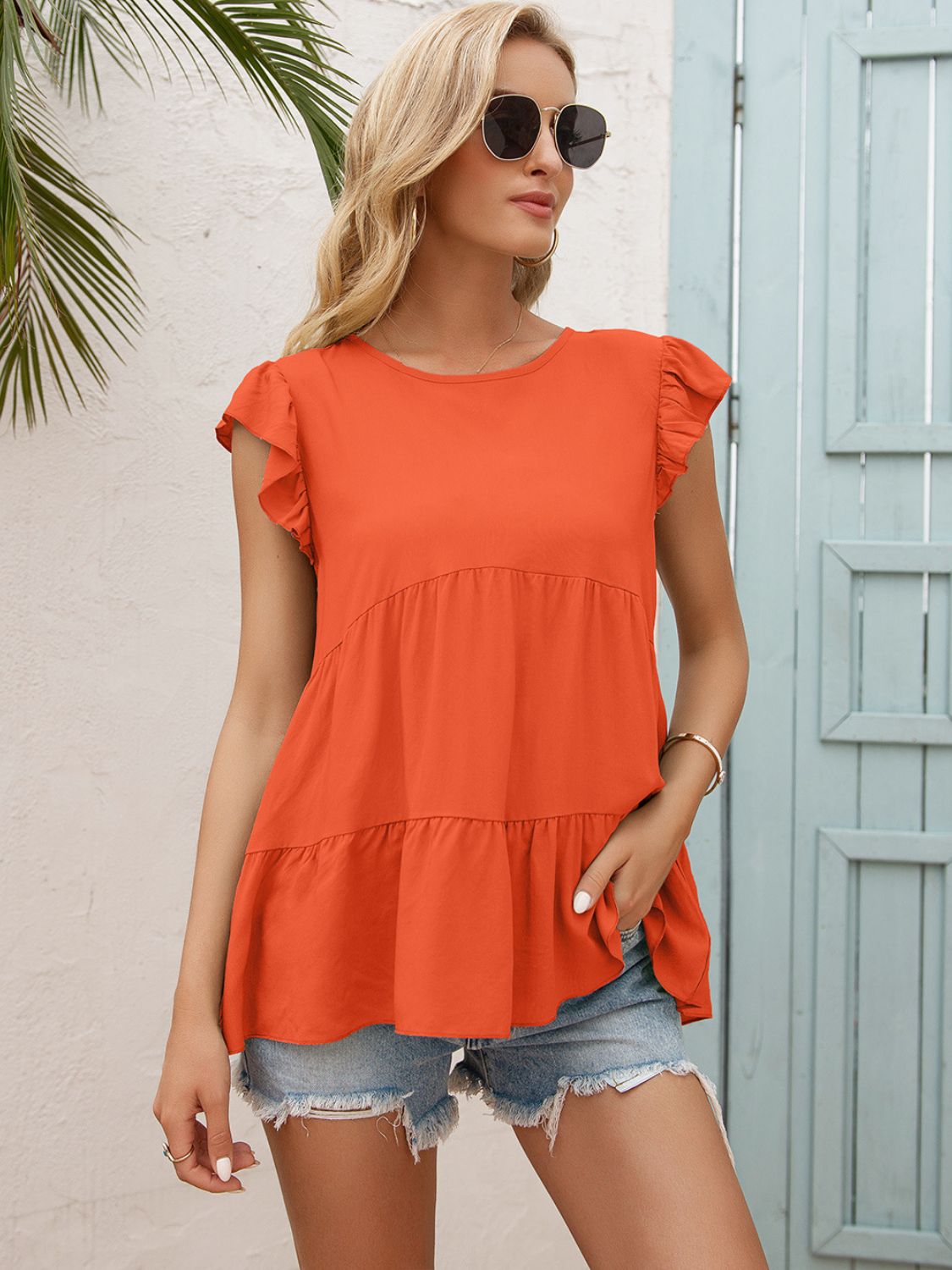 Orange tiered blouse with round neck and flutter sleeves, layered ruffle styling