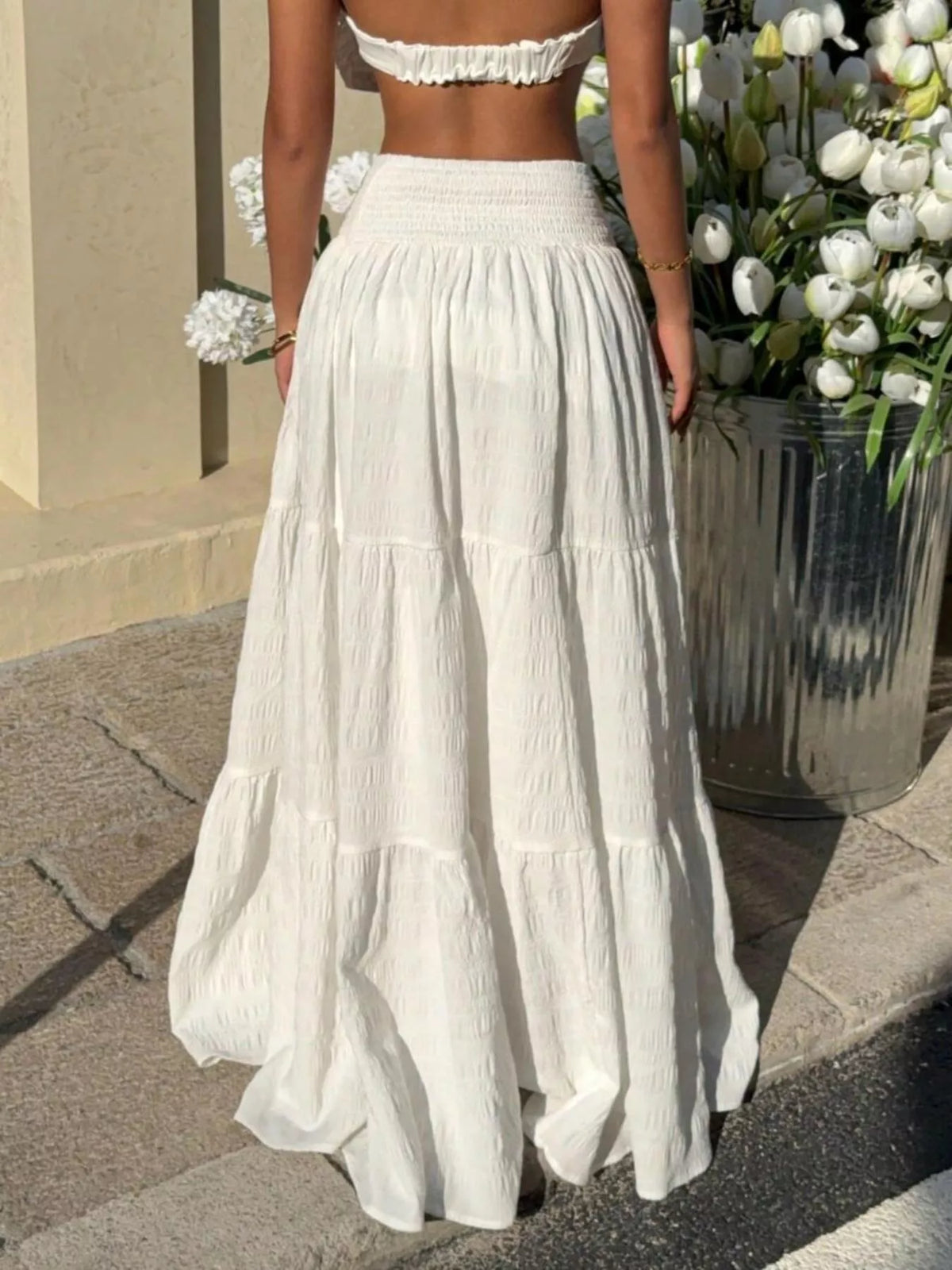 White tiered maxi skirt with smocked waistband and wide ruffle tiers