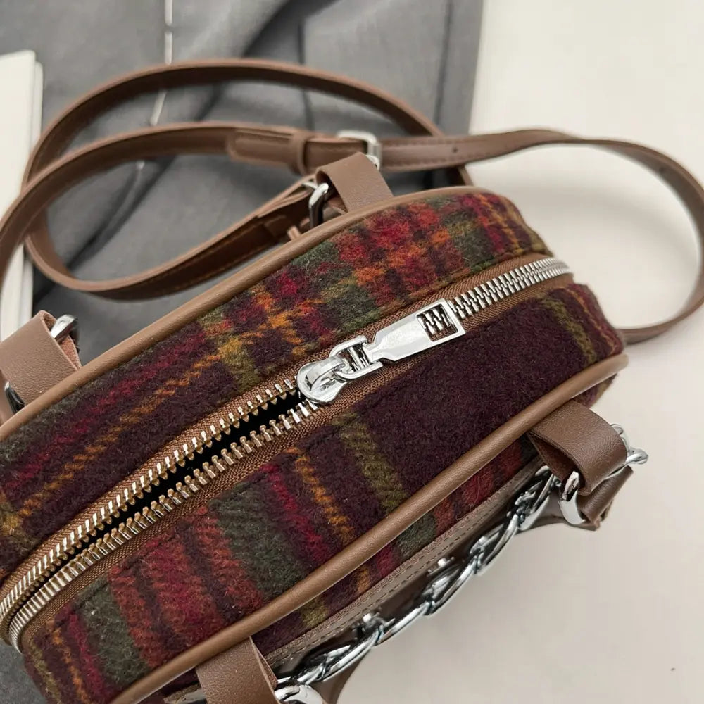 Plaid crossbody bag close-up with silver zipper, brown leather straps, and chain
