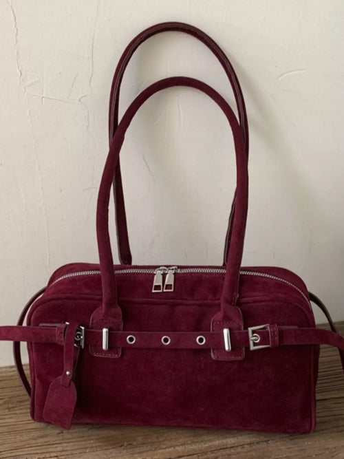 Burgundy shoulder bag with top handles, silver buckle bar, and side pouch