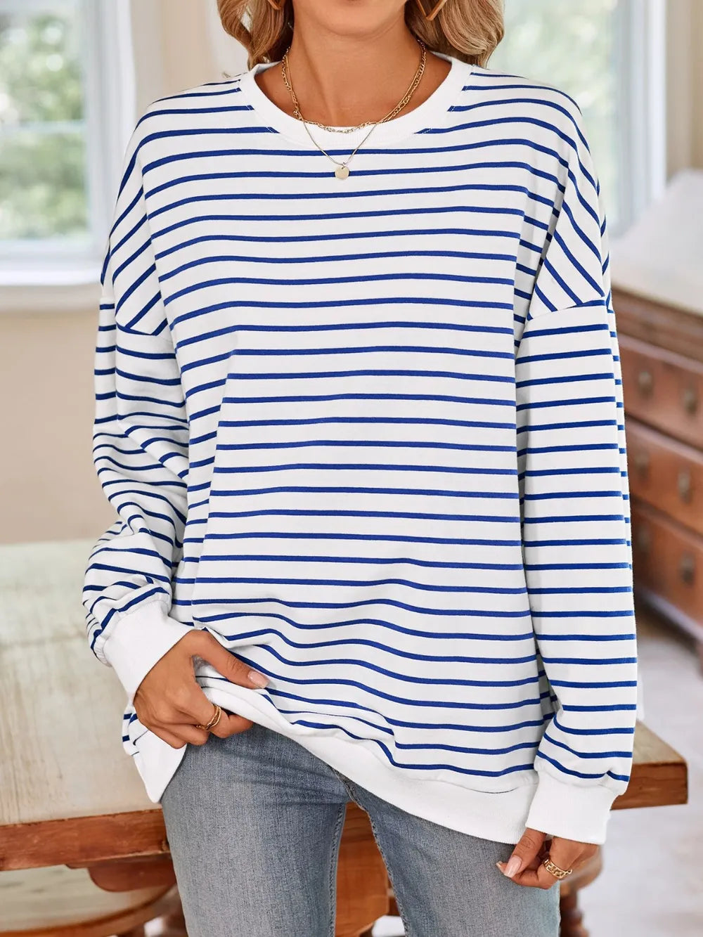White and blue striped round-neck long-sleeve sweatshirt, front view with draped hem