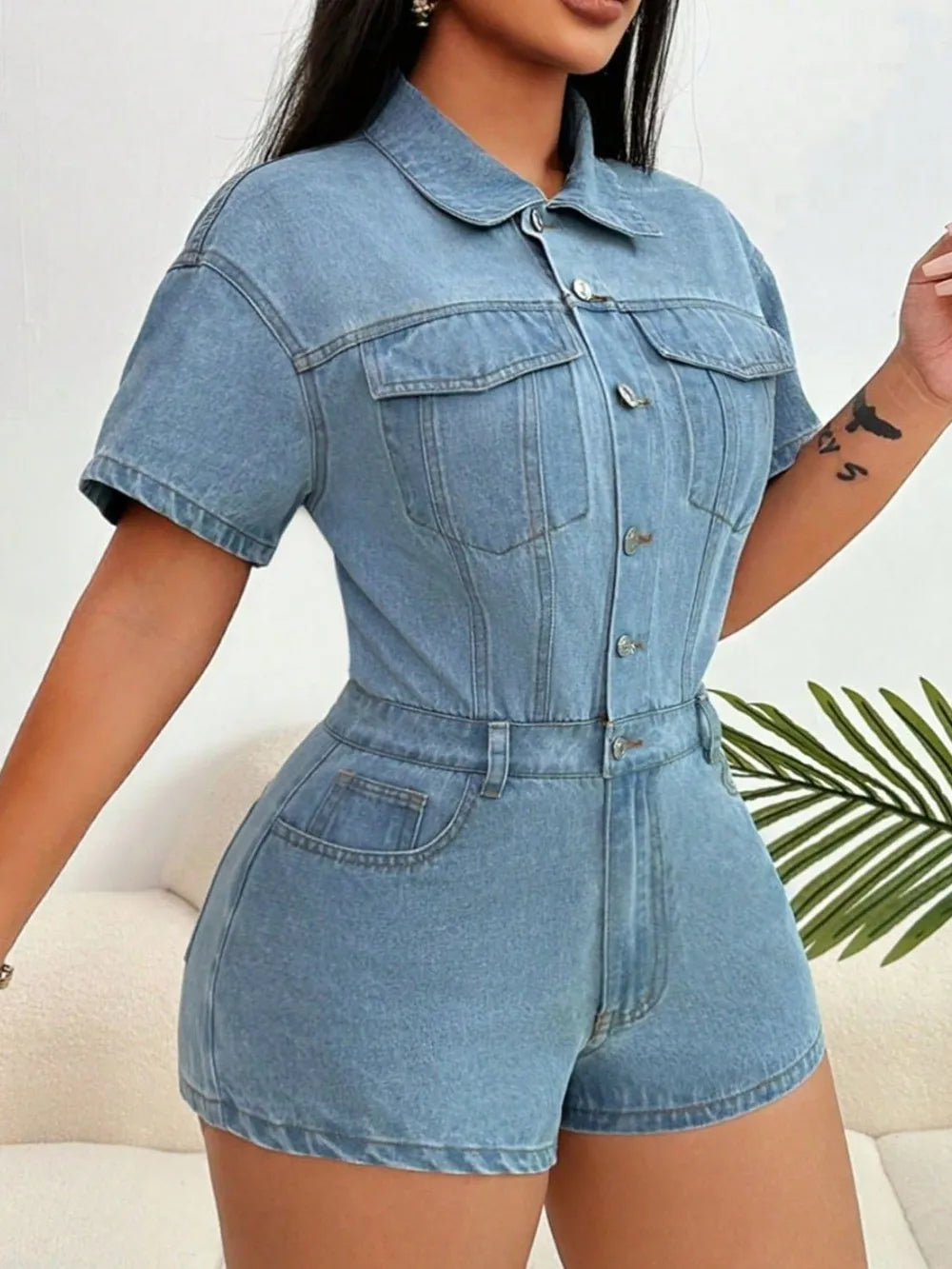 Light blue denim collared romper, short sleeves and chest flap pockets, belted waist