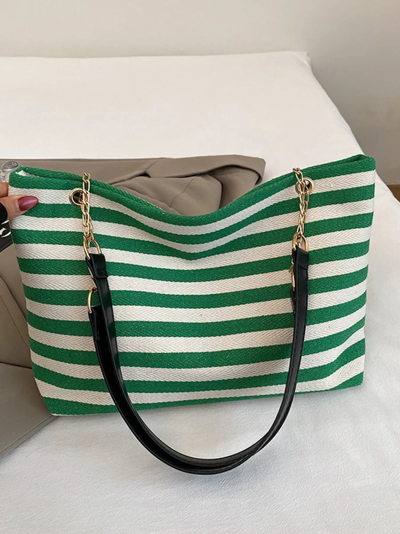 Green and white striped shoulder bag with gold chain handles and black bottom panel.