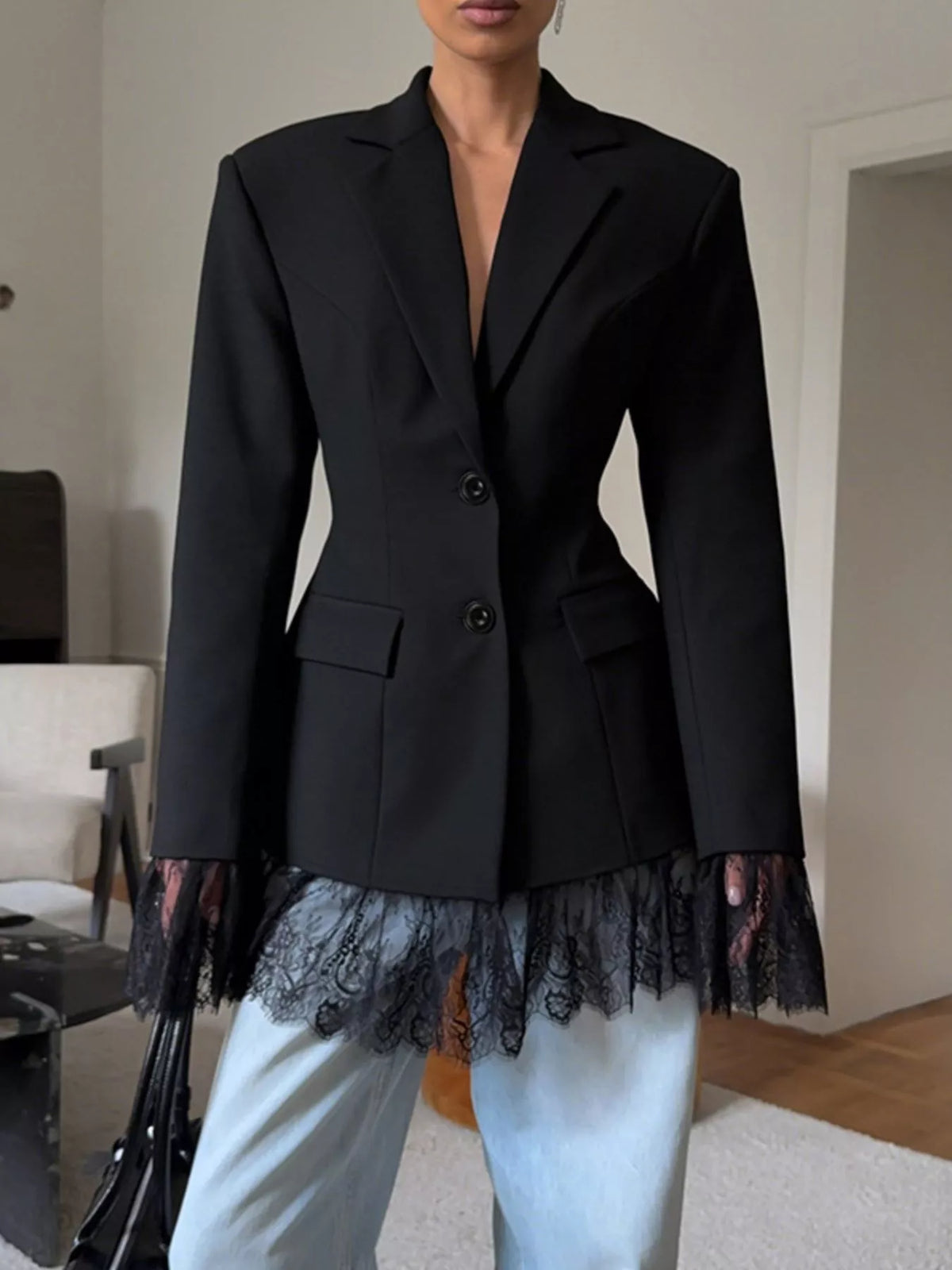Black tailored blazer with lace-trim hem and button front, flap pockets visible.