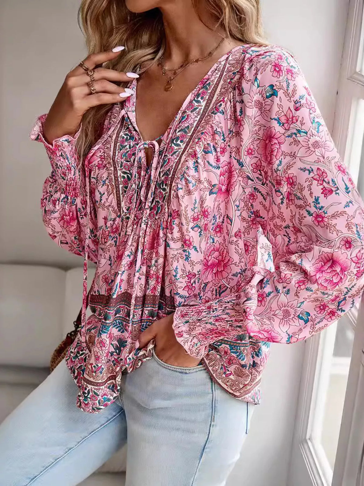 Pink floral tie-neck blouse with billowy sleeves and smocked cuffs, peplum-style hem