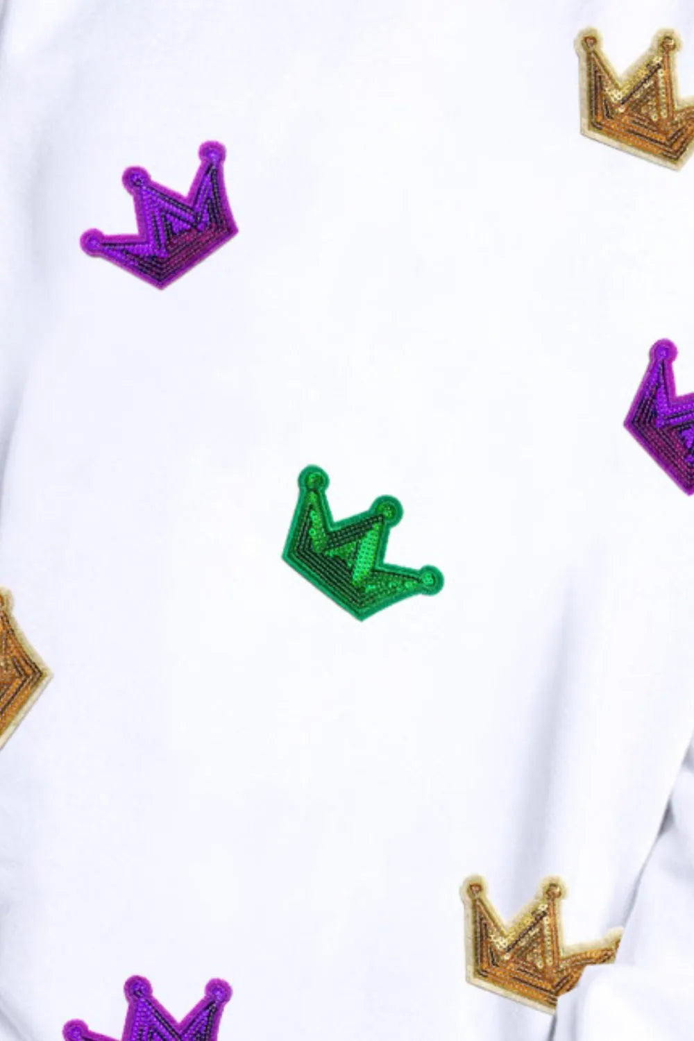 White sweatshirt close-up with purple, green, and gold sequin crown decorations