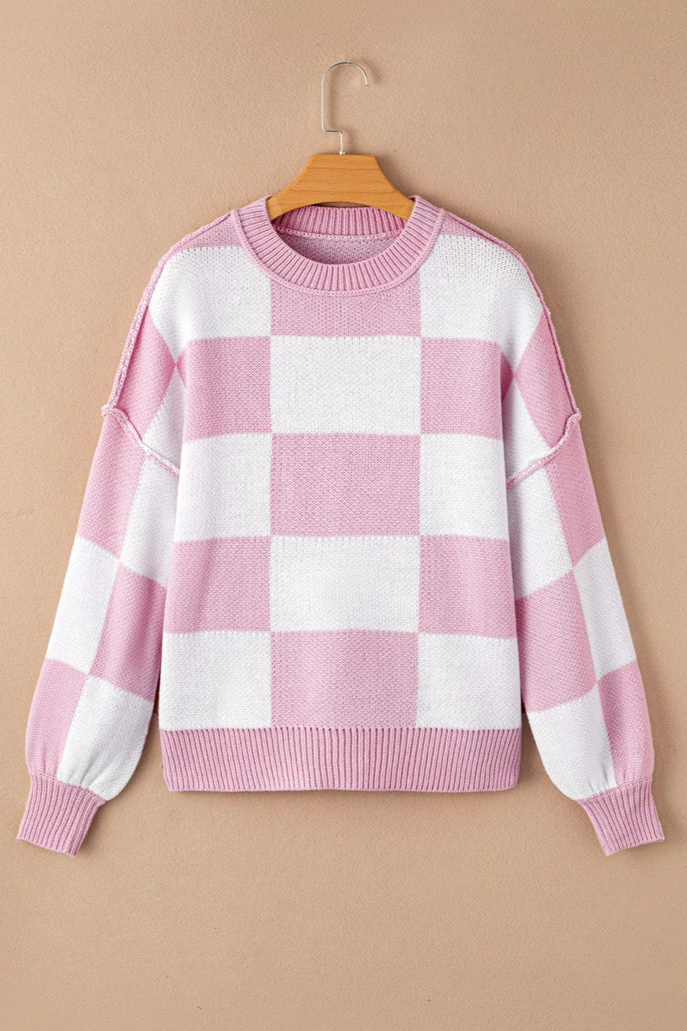 Pink and white checkered drooped-shoulder sweater with crew neck and long sleeves.