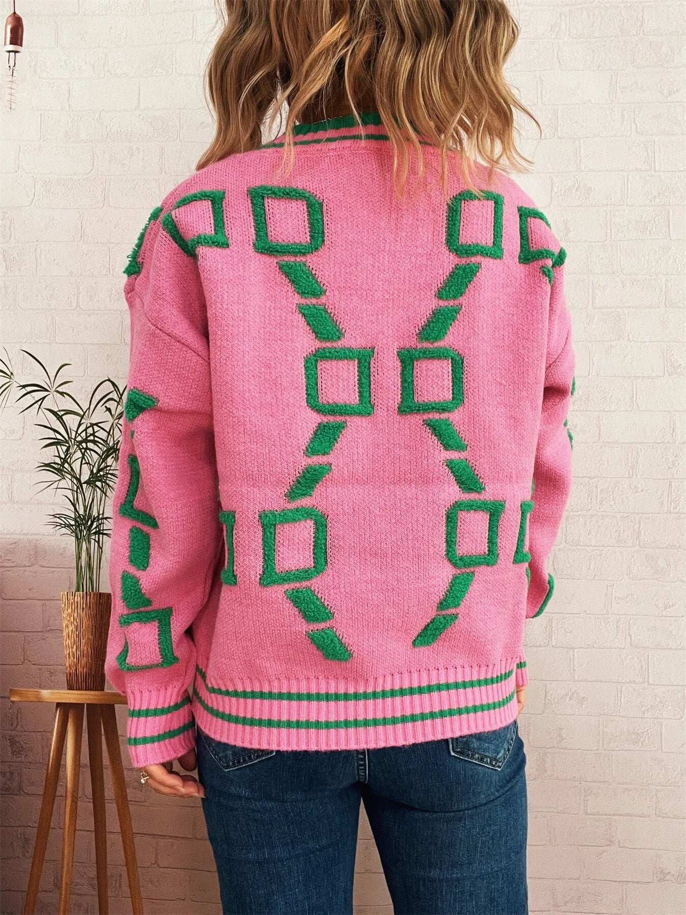 Pink long-sleeve back view sweater with green geometric squares and ribbed hem