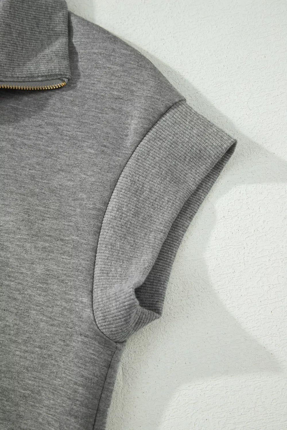 Dark gray polo tee sleeve and side seam detail from a close angle.